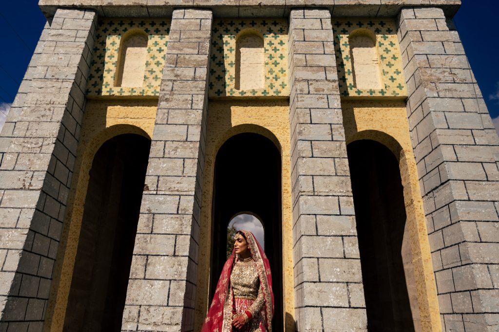 An Indian bride posing in the sun in front of a stone structure in Manitoba