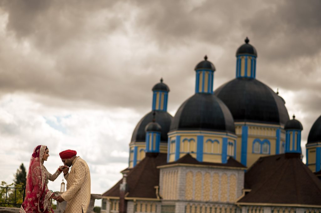 a groom, kissing his brides hand in front of a Catholic church at Cook's Creek Manitoba