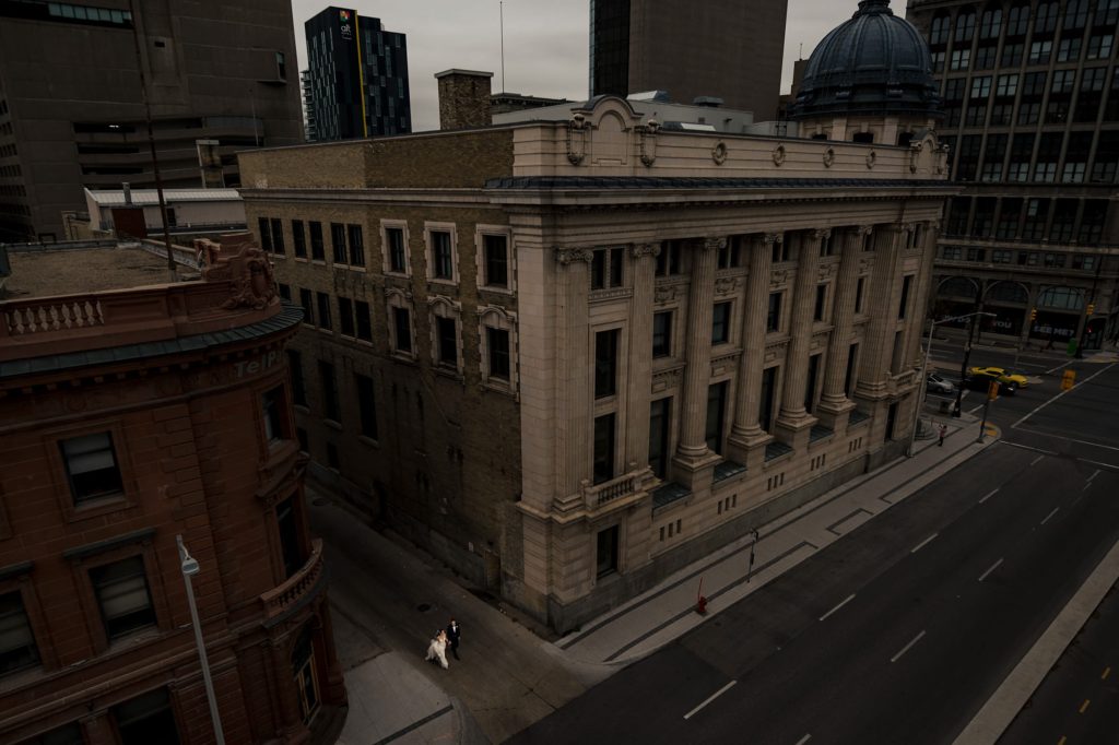 A bride and groom through an alley in downtown Winnipeg