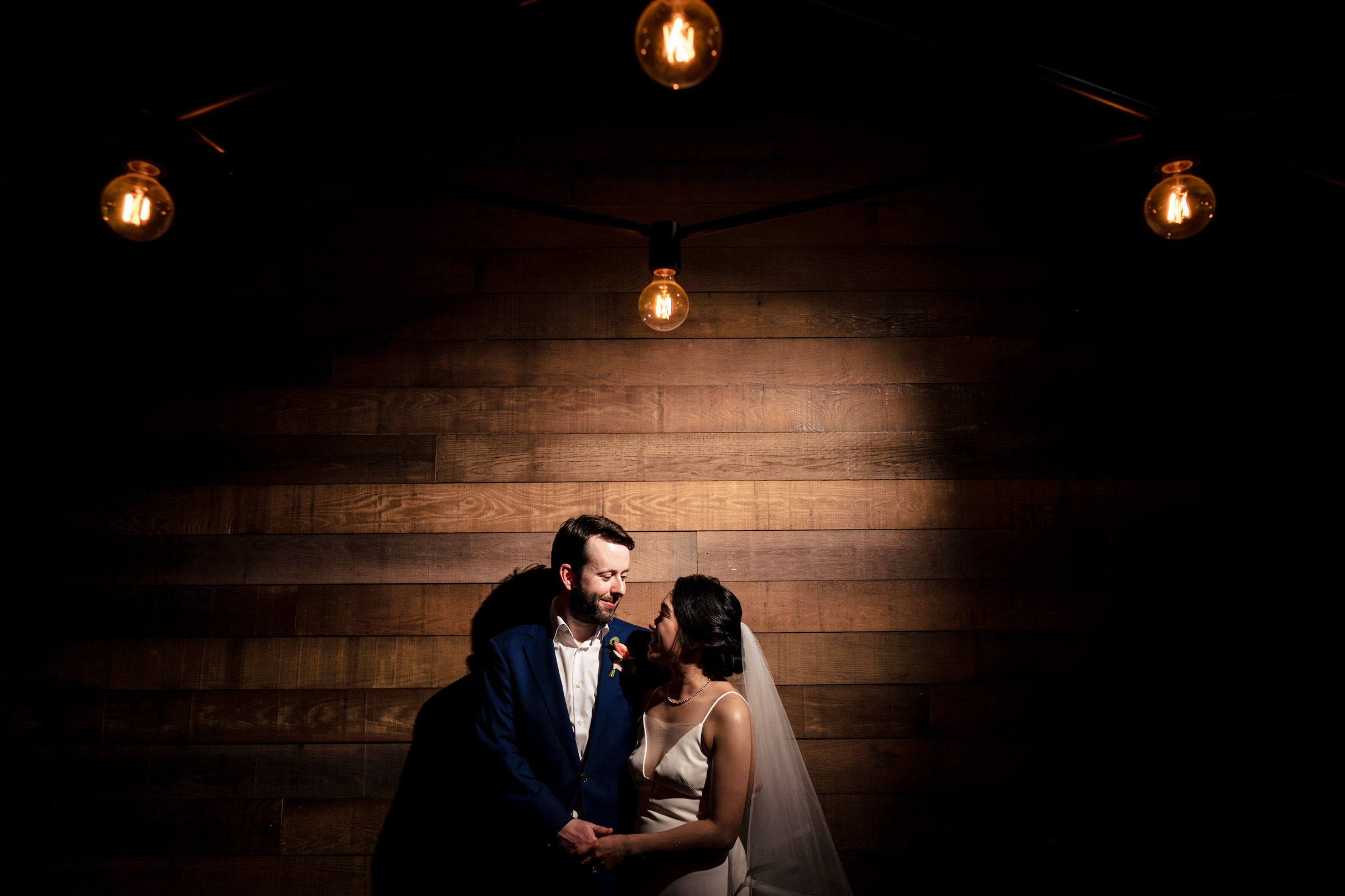 bride and groom posing at smith restaurant in winnipeg against a wooden wall