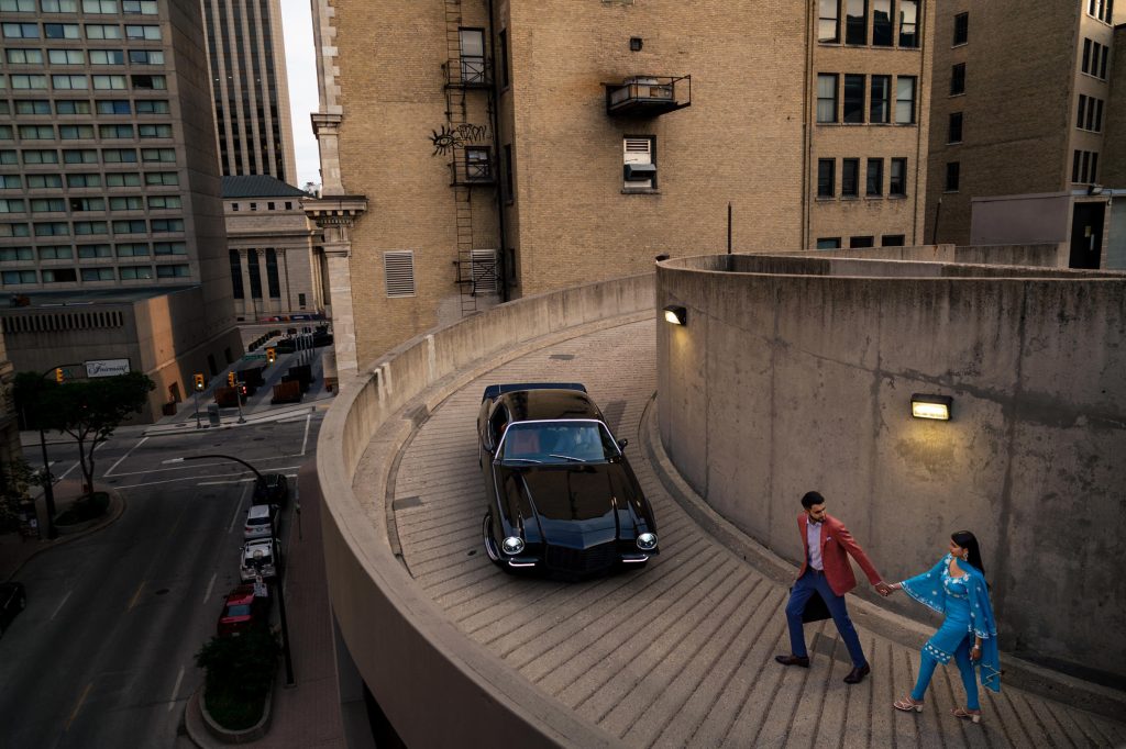 An Indian couple walking towards an old car on a parade rooftop in the Winnipeg exchange district