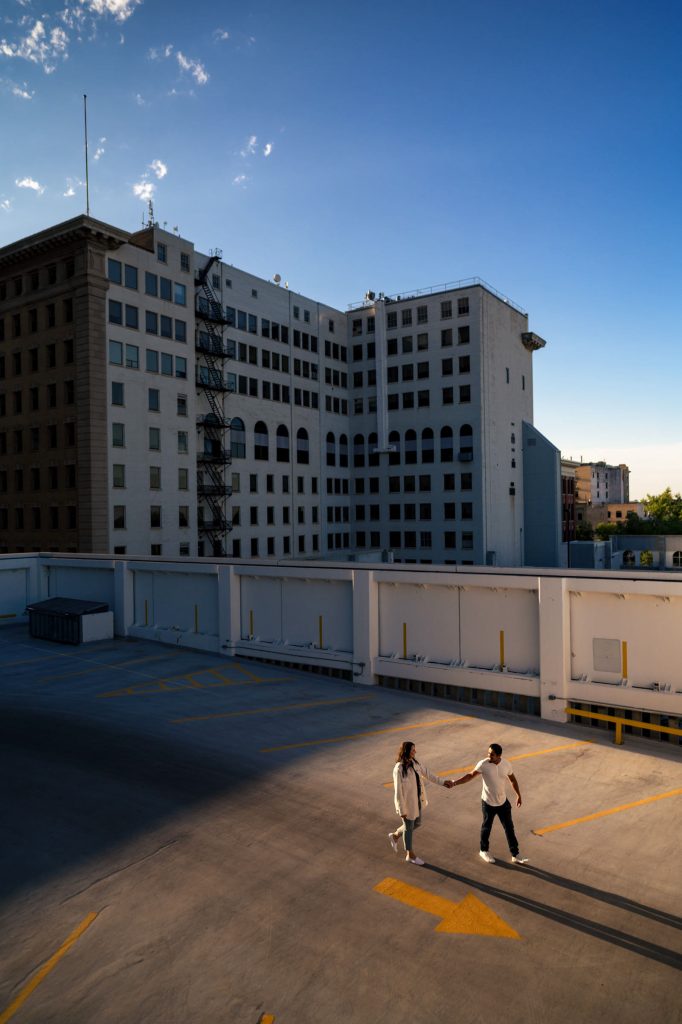 A couple holding hands walking on a rooftop parade in downtown Winnipeg during an engagement session