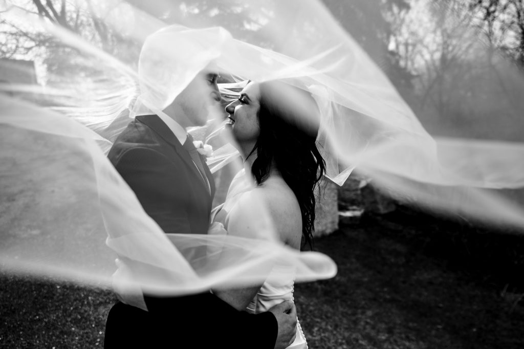 A bride and groom, embracing and smiling in a black-and-white wedding photo