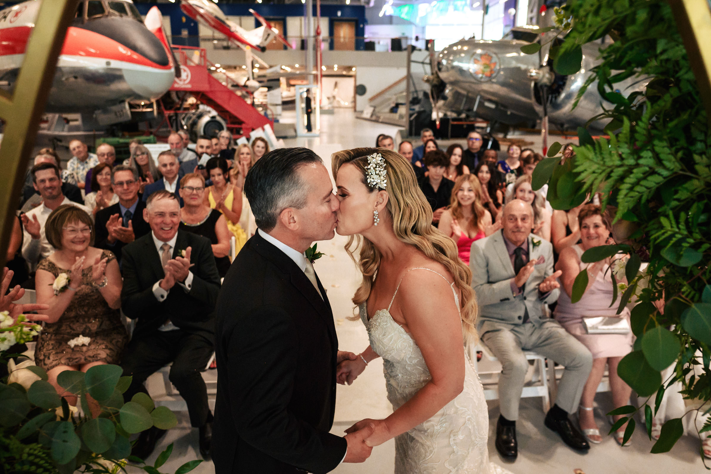 Bride and groom kiss at a Winnipeg wedding venue with an aviation theme.