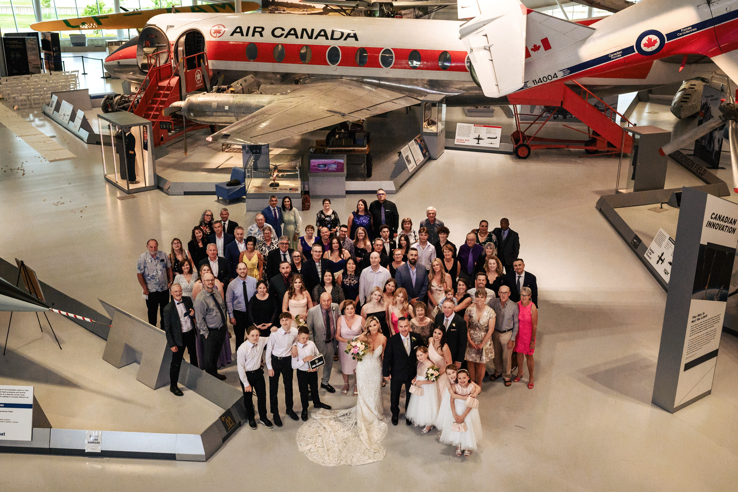 Wedding group photo at a vintage aircraft in Winnipeg wedding venues museum.