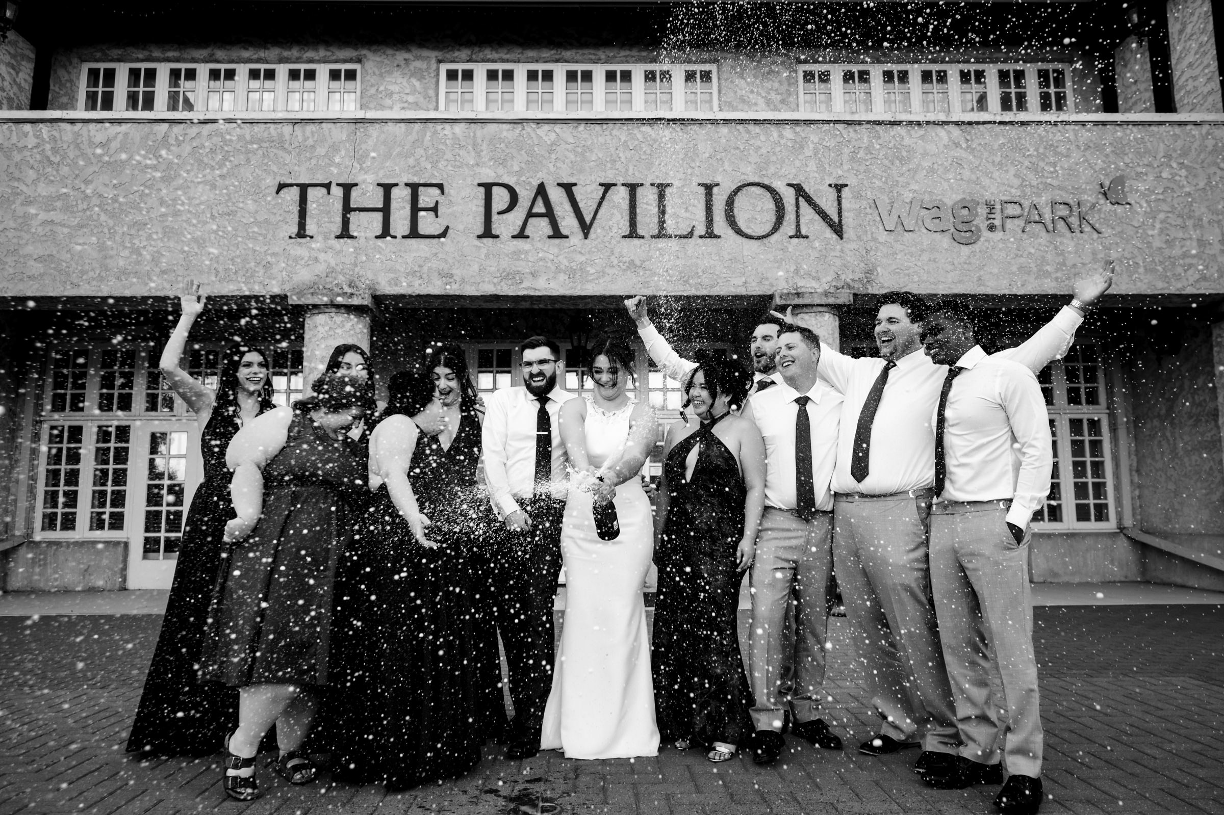 Group celebrating outside "The Pavilion," a top Winnipeg wedding venue, confetti falling around.