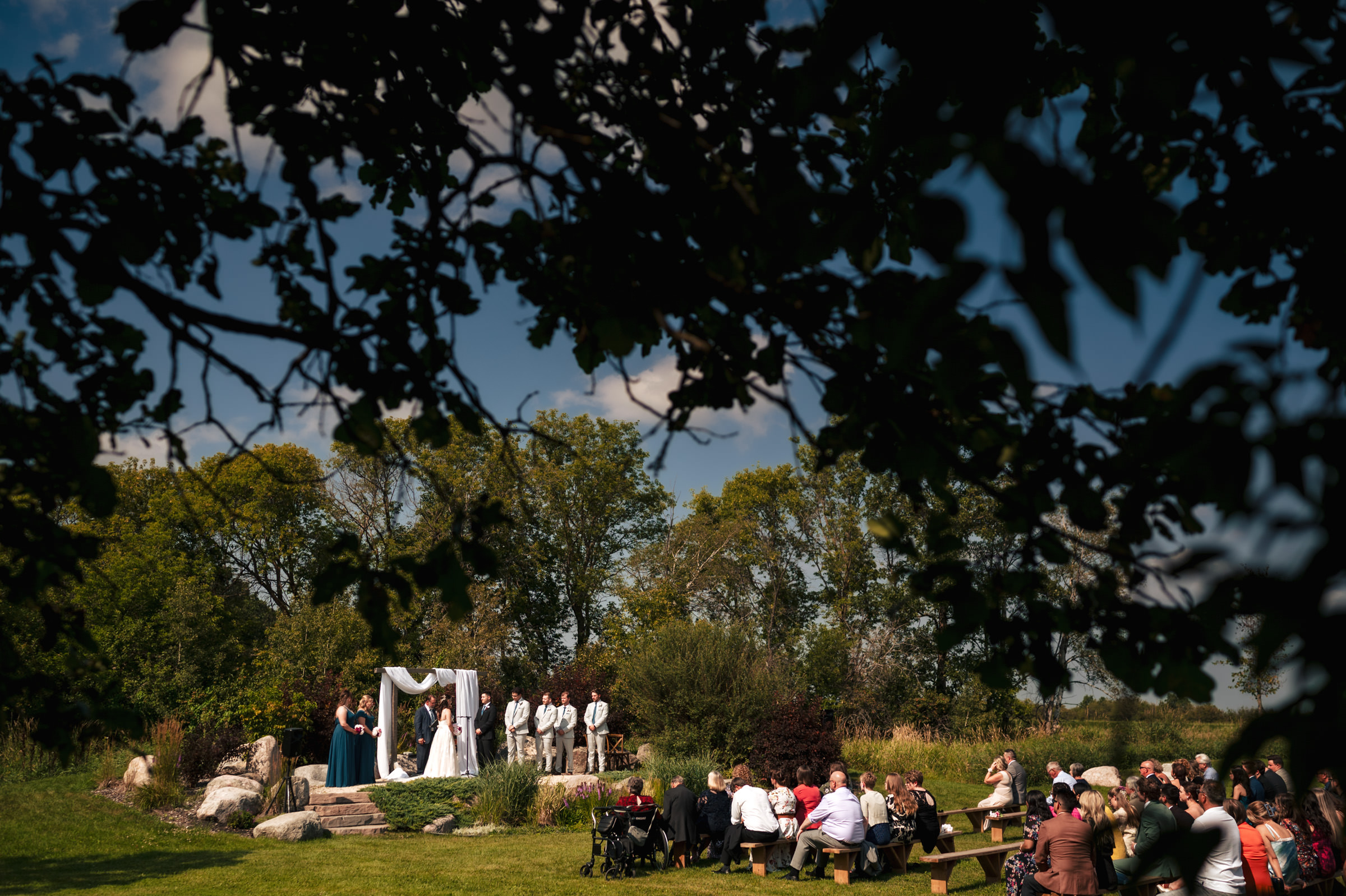 Outdoor wedding ceremony in a Winnipeg venue with guests seated and couple at the altar.