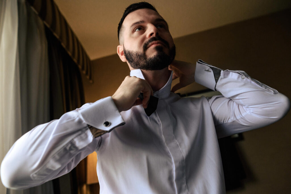 Man adjusting his collar, dressed for a fall wedding in Winnipeg.