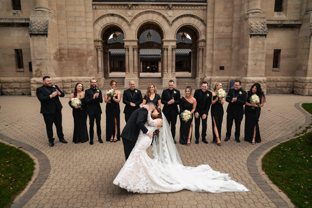 Bride and groom kiss at a fall wedding in Winnipeg, with smiles all around.