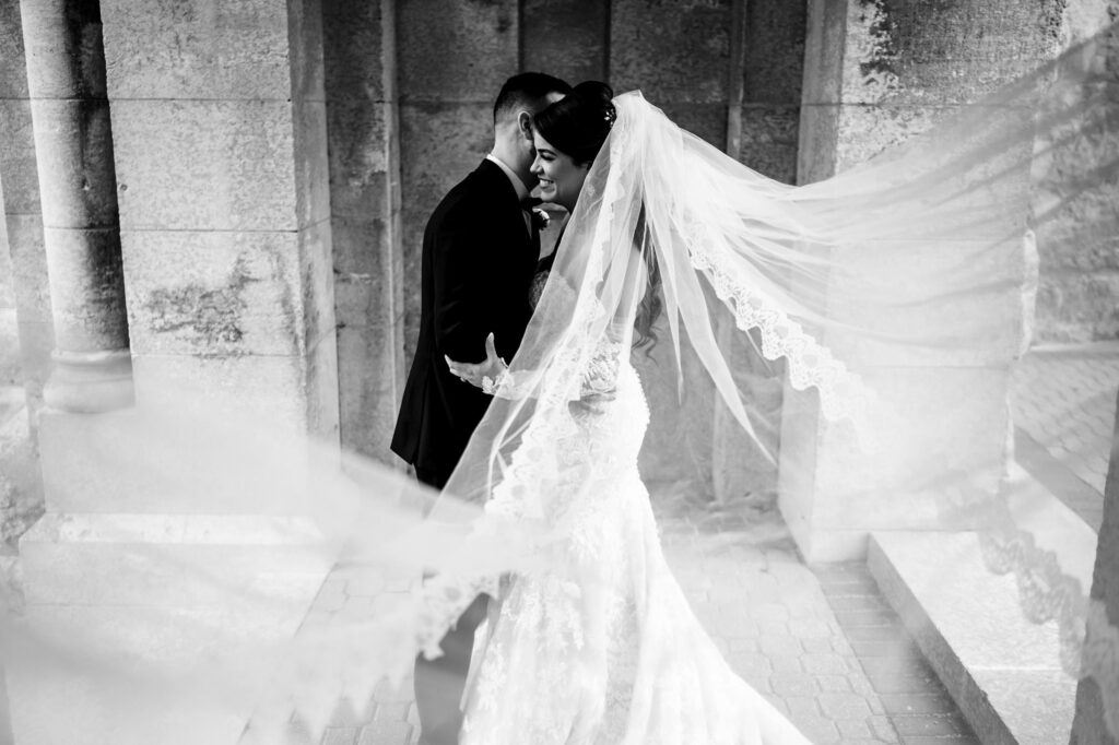 Bride and groom embrace, veil flowing in a black and white fall wedding in Winnipeg.