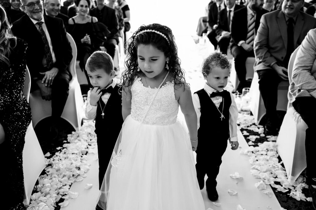 Three children in formal attire walk down the aisle at a fall wedding in Winnipeg.
