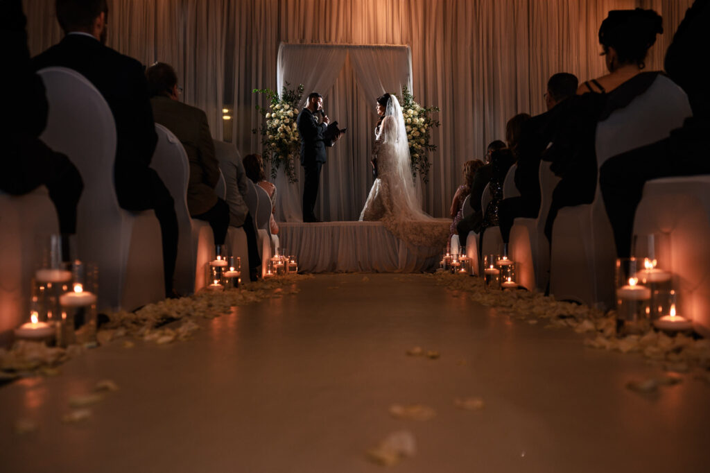 Bride and groom stand at altar during fall wedding in Winnipeg, surrounded by guests and candles.