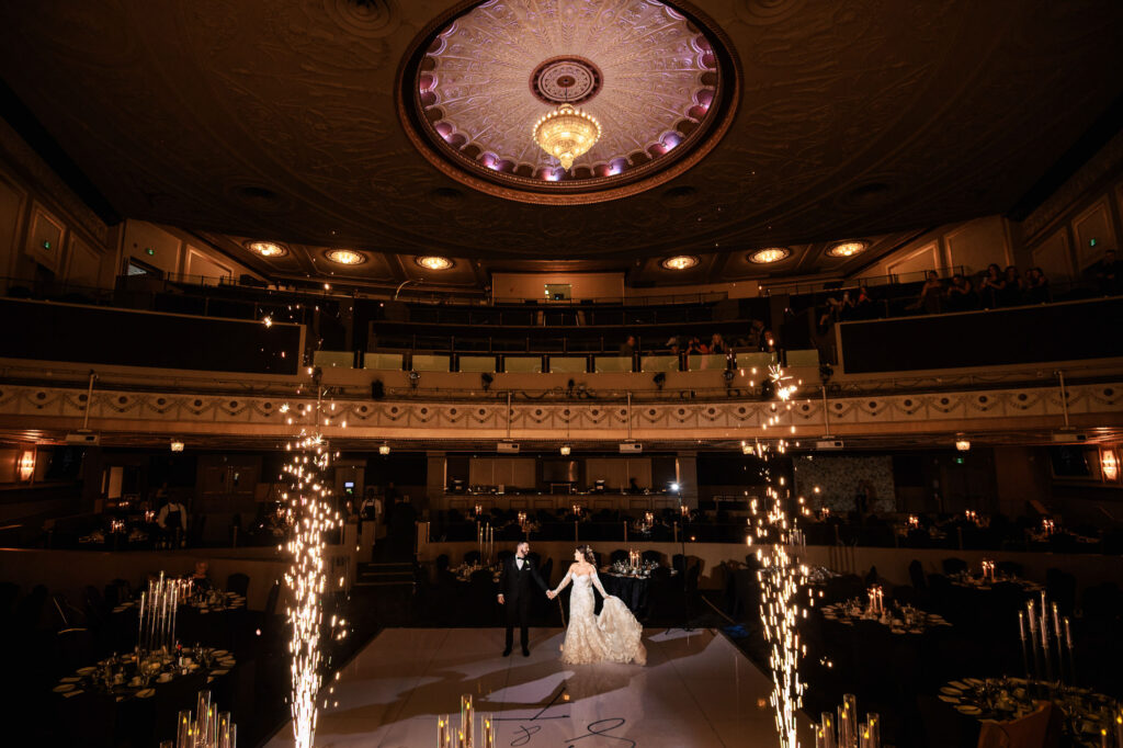 Bride and groom dance on stage with sparklers at a fall wedding in Winnipeg theater.