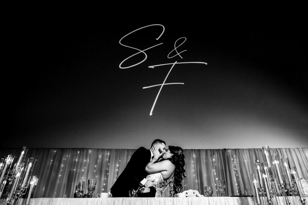 Couple kissing at a fall wedding in Winnipeg, with initials "S & F" projected above them.