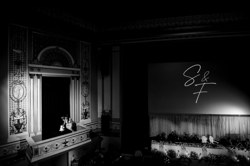 A couple kisses in a balcony at a Winnipeg theater; "S & F" light up the fall wedding screen.