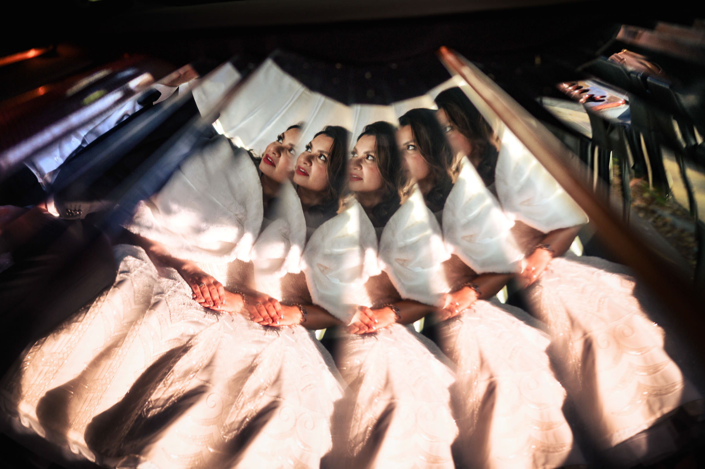 Women in their favorite wedding photos are reflected multiple times in a kaleidoscope-like fashion, creating a repeated pattern. They sit close together, hands clasped, with light and shadow adding a dramatic effect.