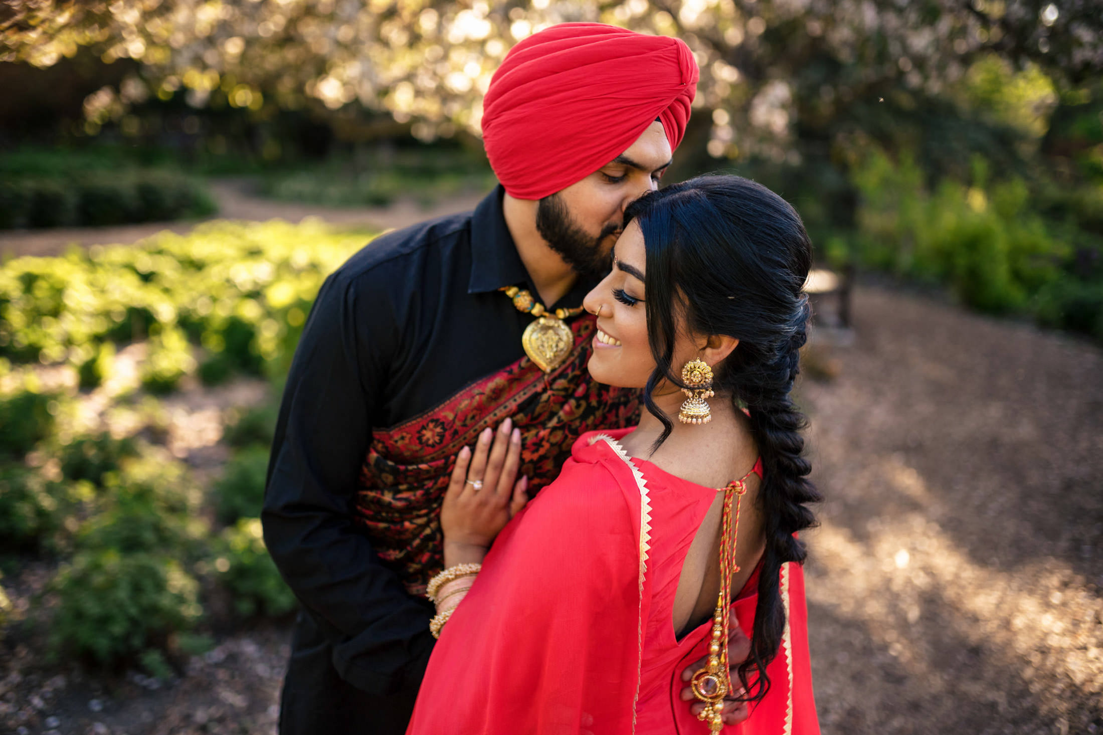 A couple in traditional attire shares a tender moment outdoors.