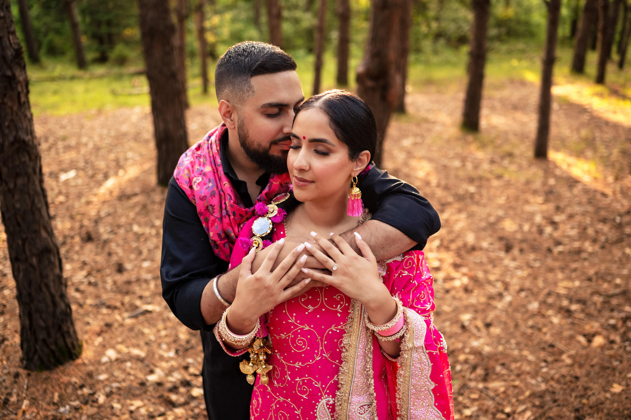 A couple embracing in a forest, wearing colorful traditional attire.
