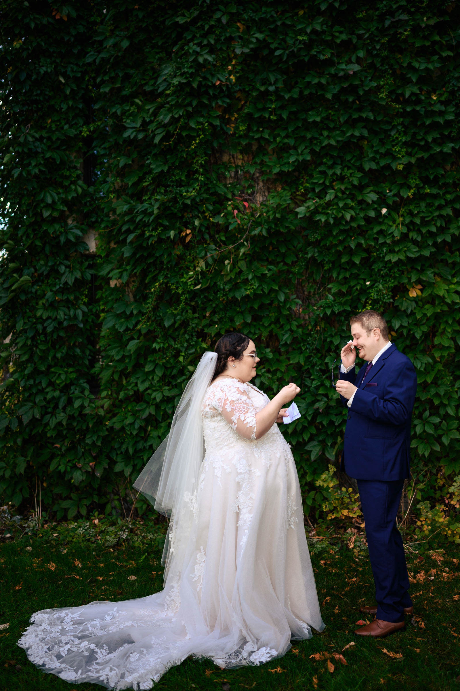 Bride and groom exchanging vows in front of a leafy green backdrop.