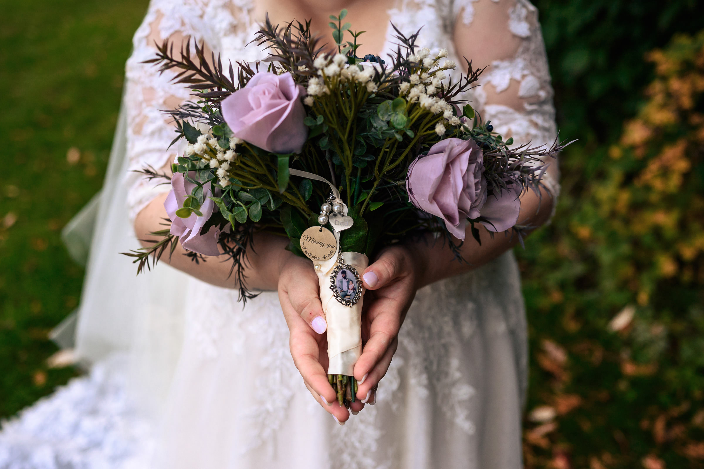 Bride holding bouquet of purple roses and greenery.