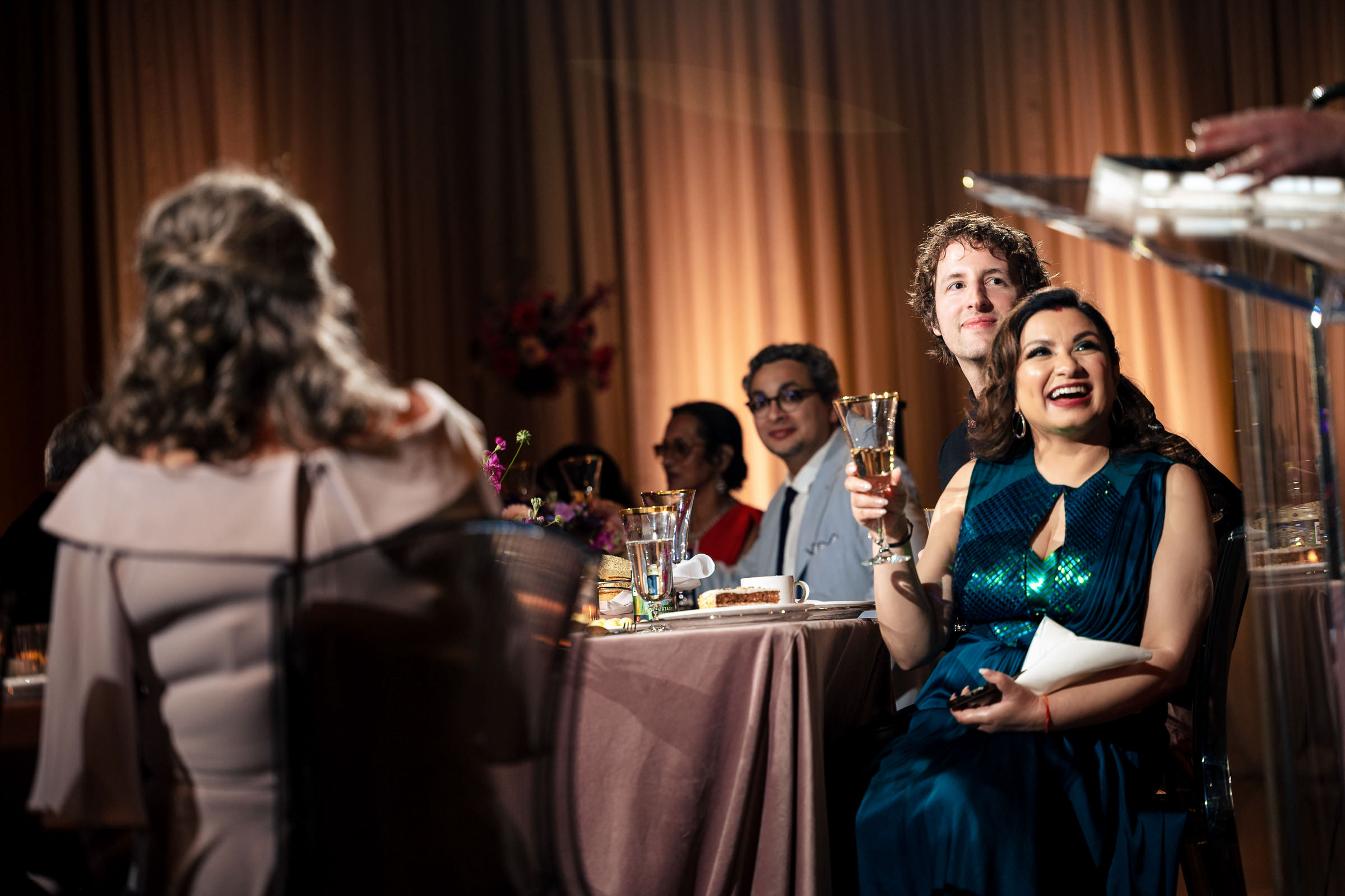 Guests at a Winnipeg wedding banquet toast, while one person smiles broadly.
