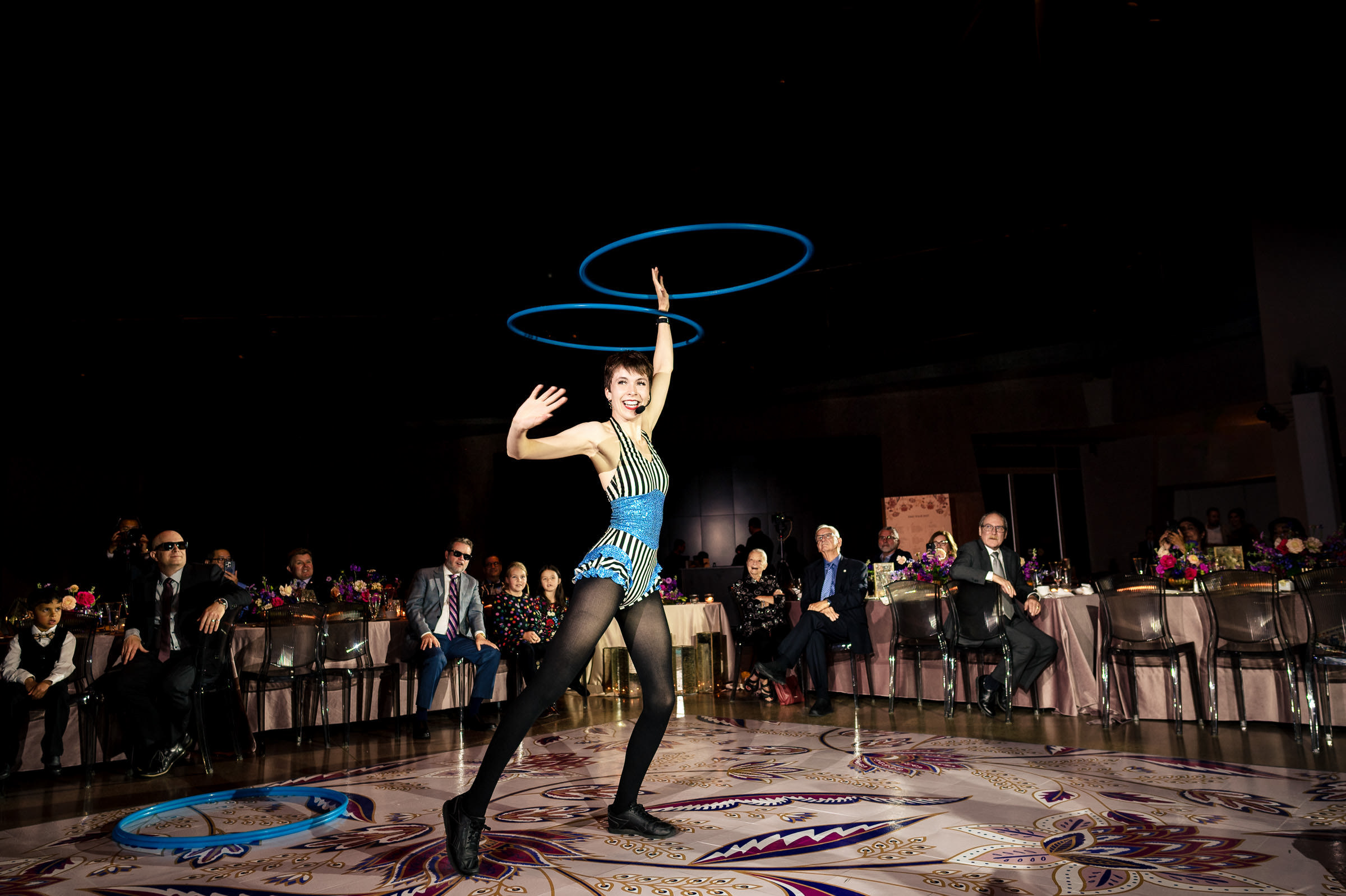 Performer hula hooping at a Winnipeg wedding, dazzling the indoor audience.