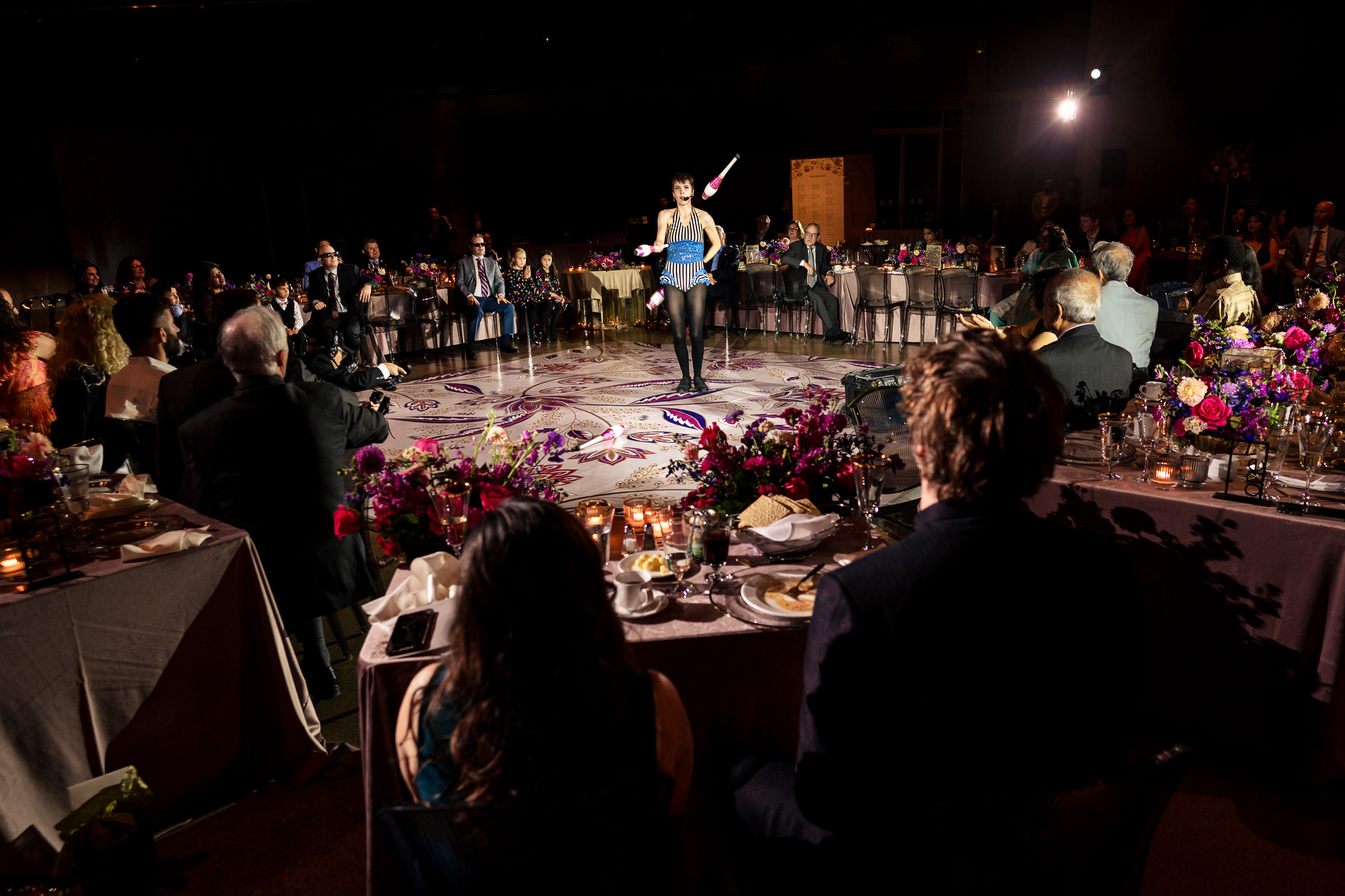Performer juggling at a formal Winnipeg wedding, with an audience seated around.