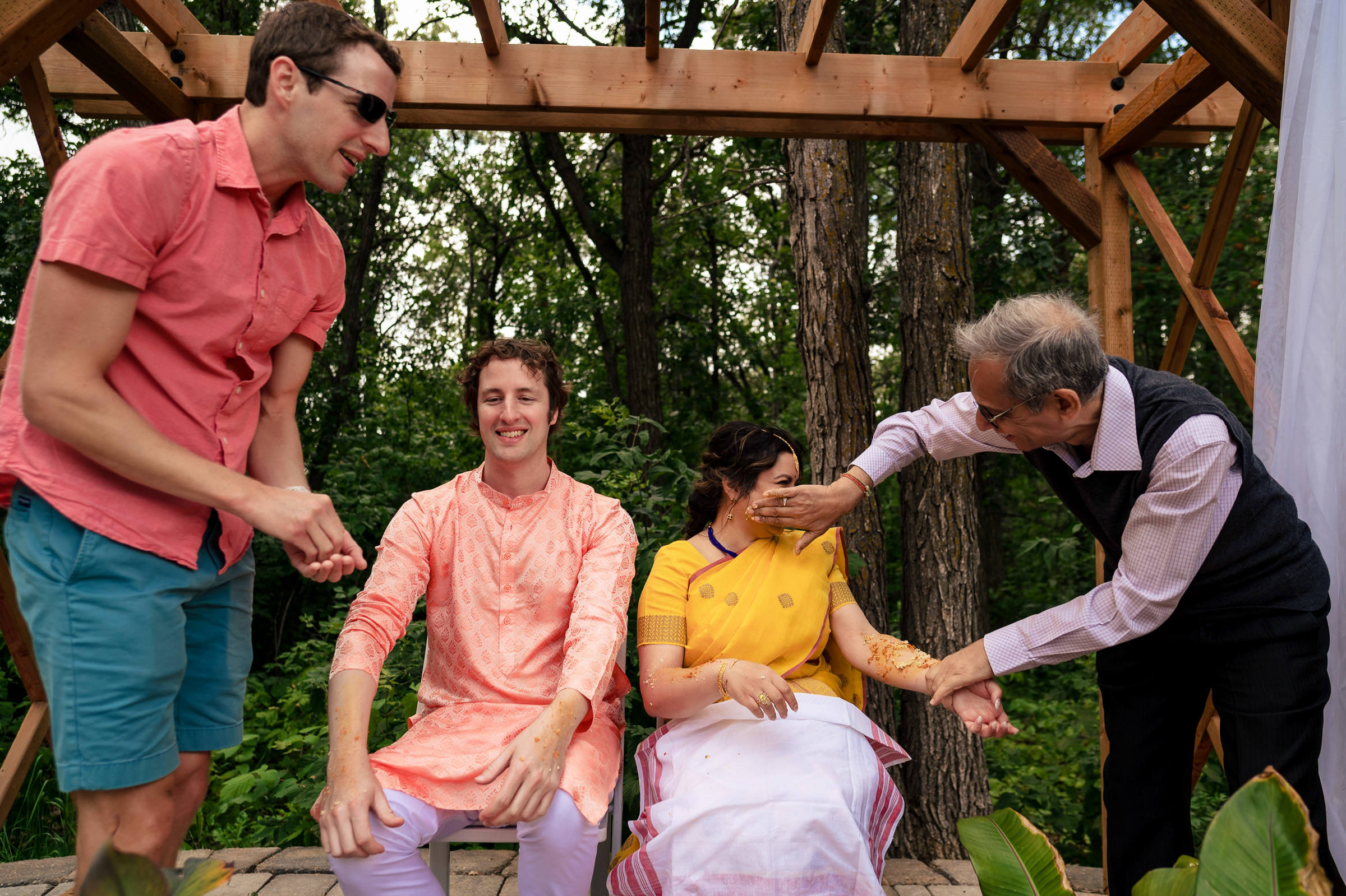 People at a Winnipeg wedding outdoors, applying turmeric to cheeks in a ceremonial setting.