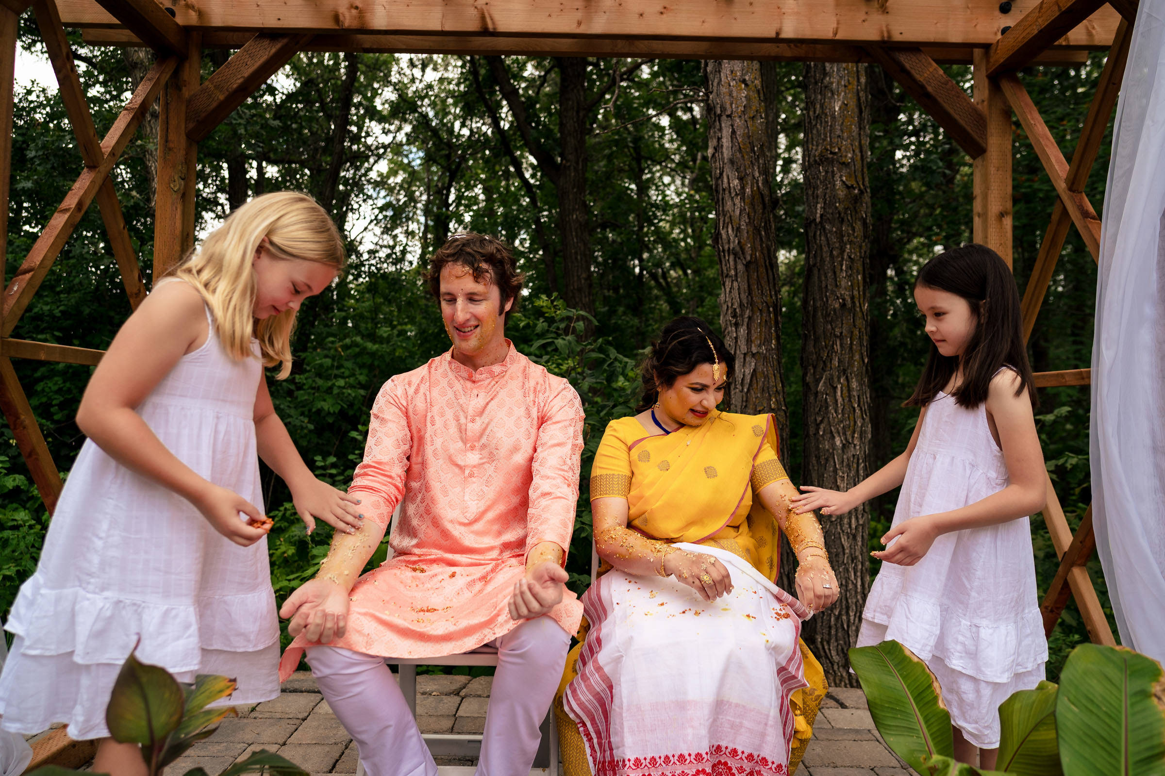 Two children sprinkle petals on a couple in festive attire at a Winnipeg wedding.