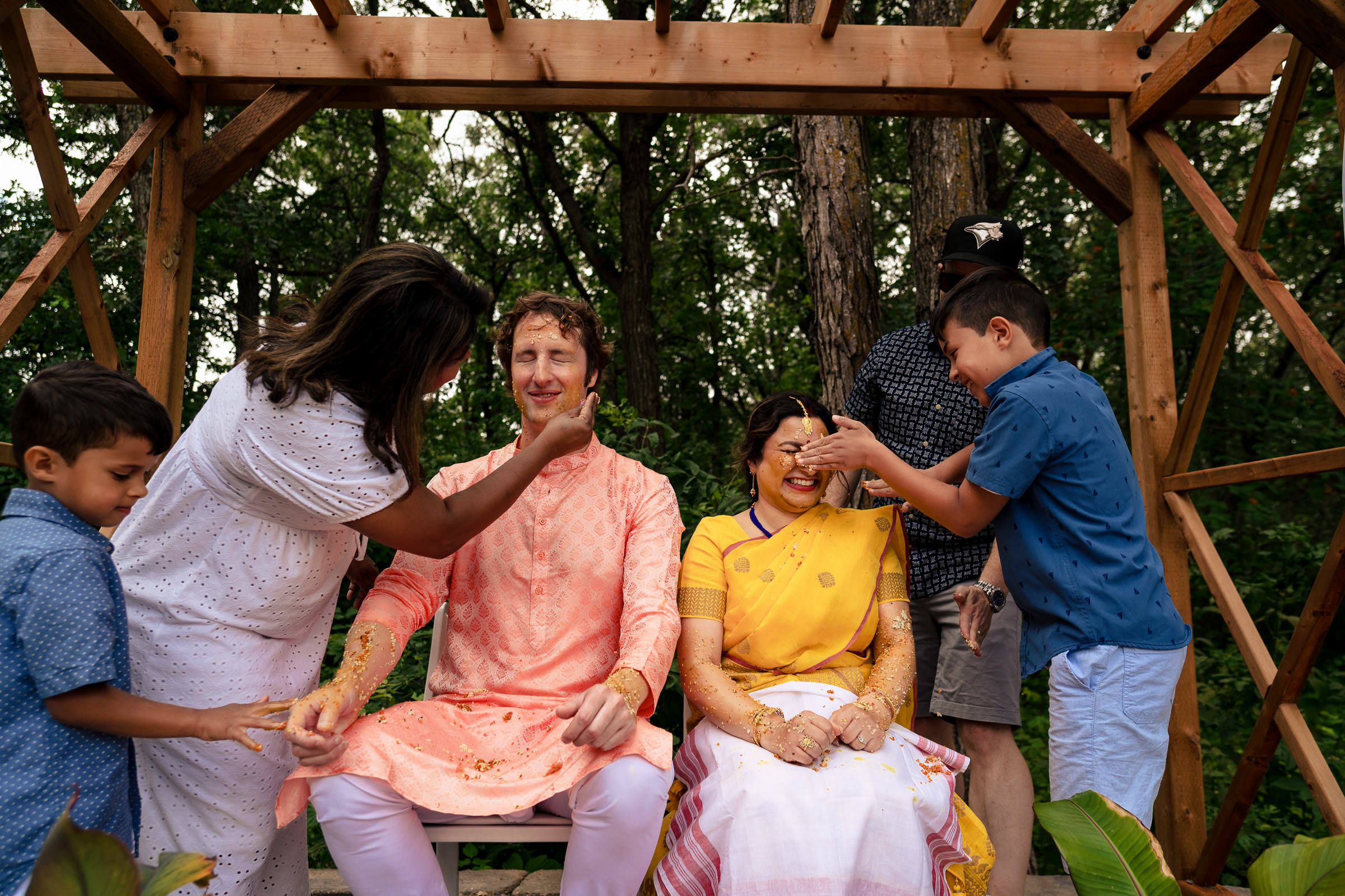 At a Winnipeg wedding, two people enjoy turmeric paste at an outdoor ceremony.