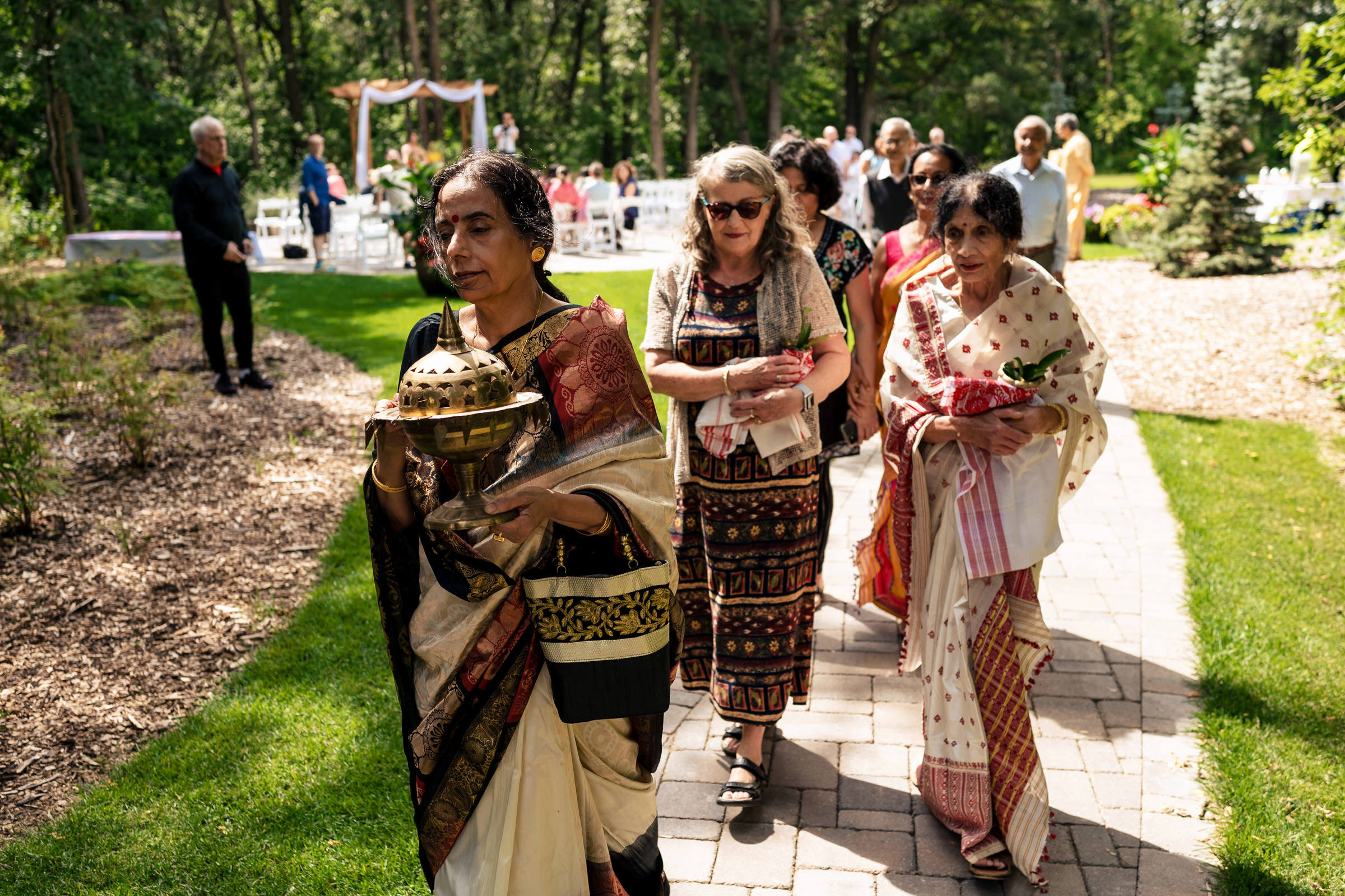 People at a Winnipeg wedding garden, some in traditional attire, holding ceremonial items.