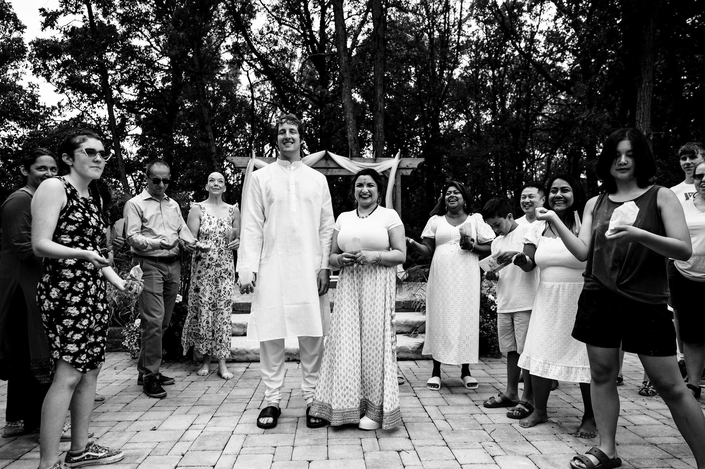 Group of people outdoors at a Winnipeg wedding, smiling in traditional attire on a stone path.