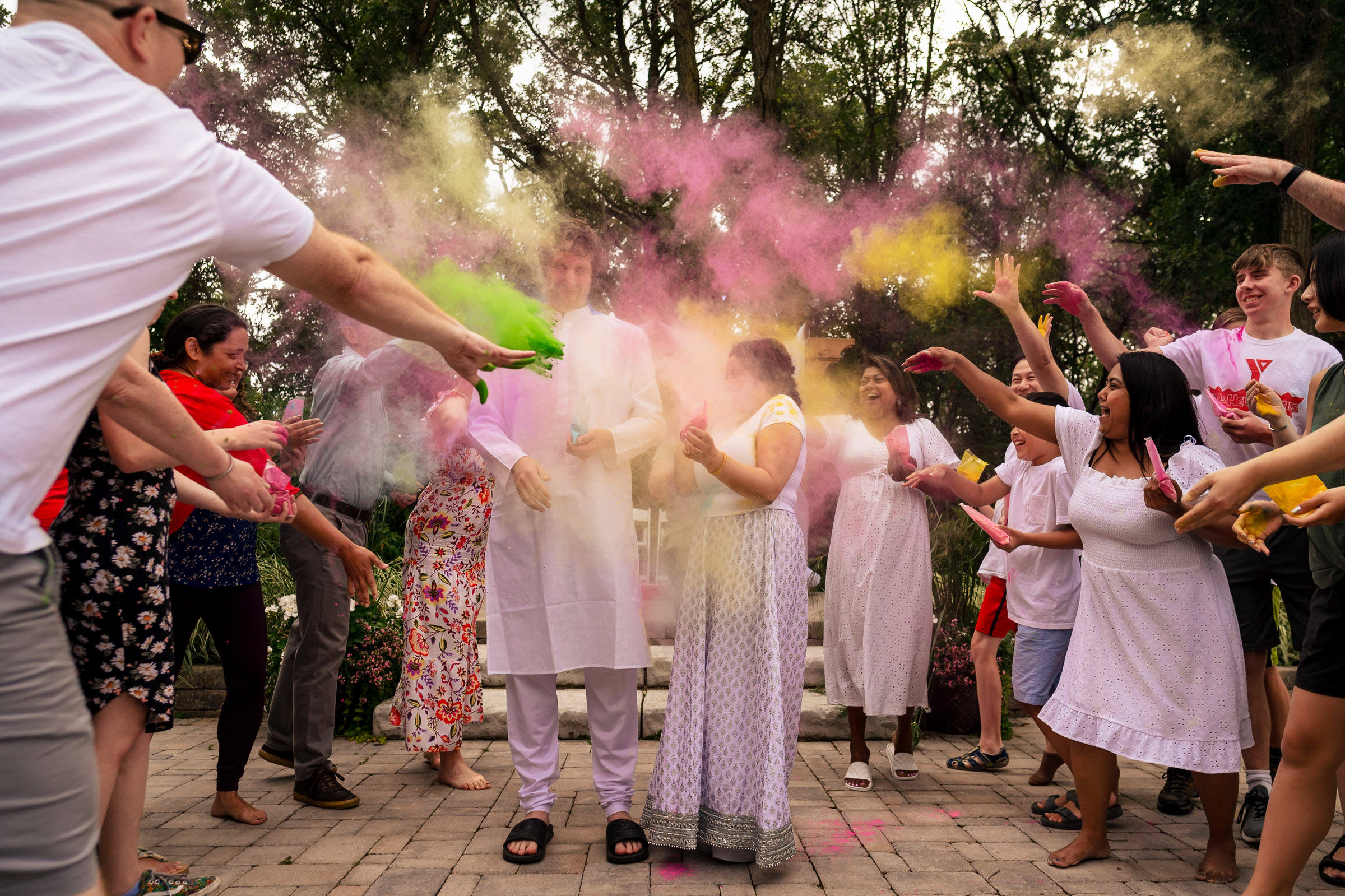 People celebrating with colorful powder outdoors during a Winnipeg wedding Holi festival.
