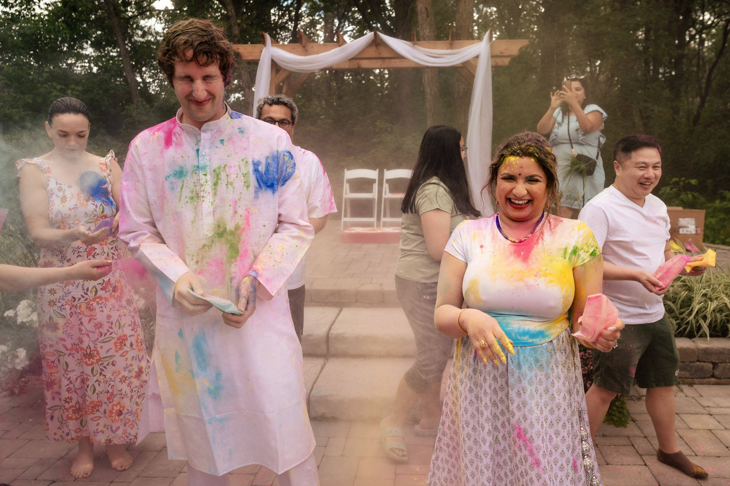 Winnipeg wedding revelers in colorful attire celebrate with vibrant powder outdoors.