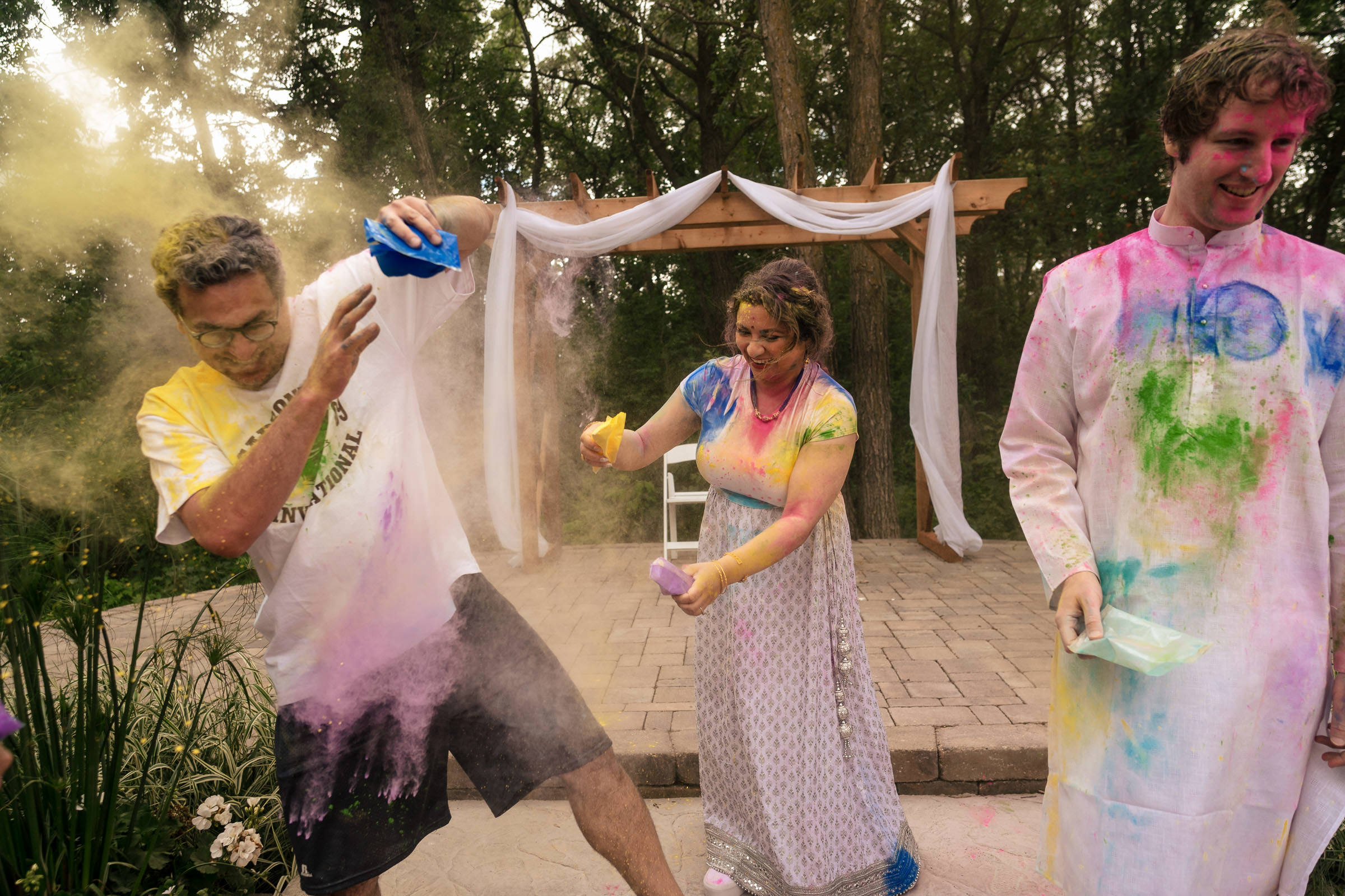 People joyfully tossing colorful powders at each other at a Winnipeg wedding.
