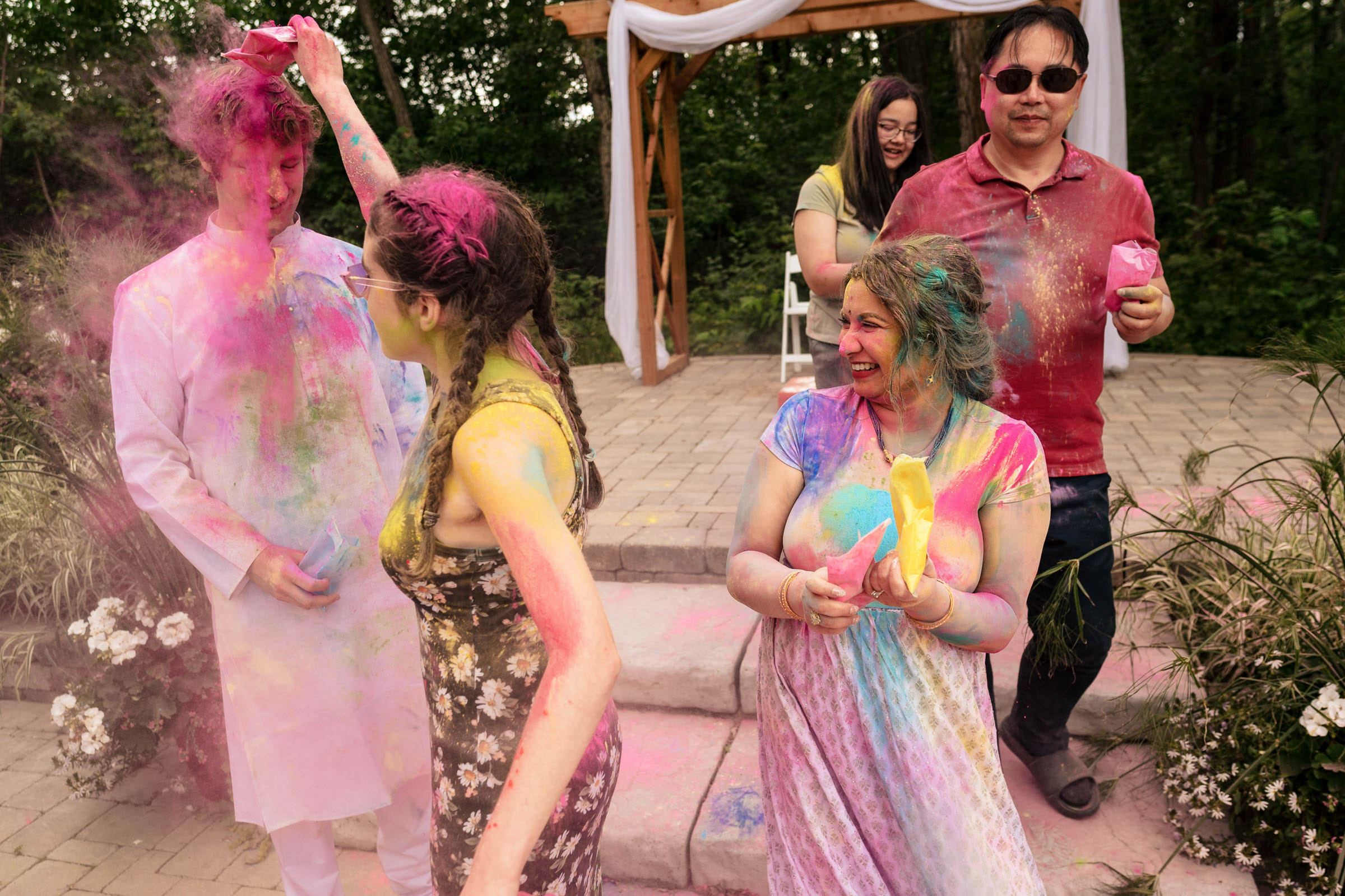 People celebrate with colorful powder outdoors, smiling like a joyful Winnipeg wedding.
