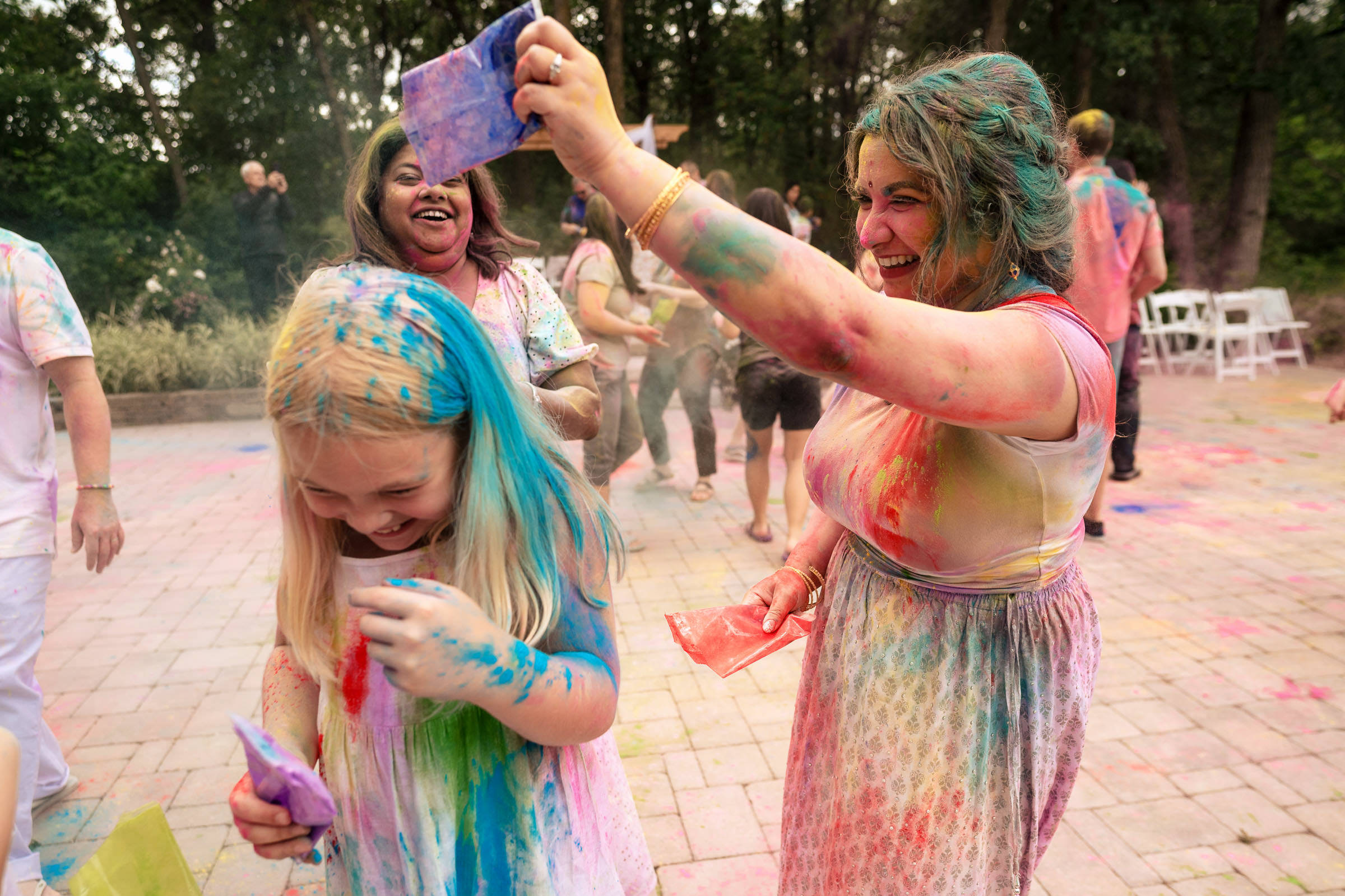 Group at a Winnipeg wedding, joyfully covered in colorful powders celebrating outdoors.