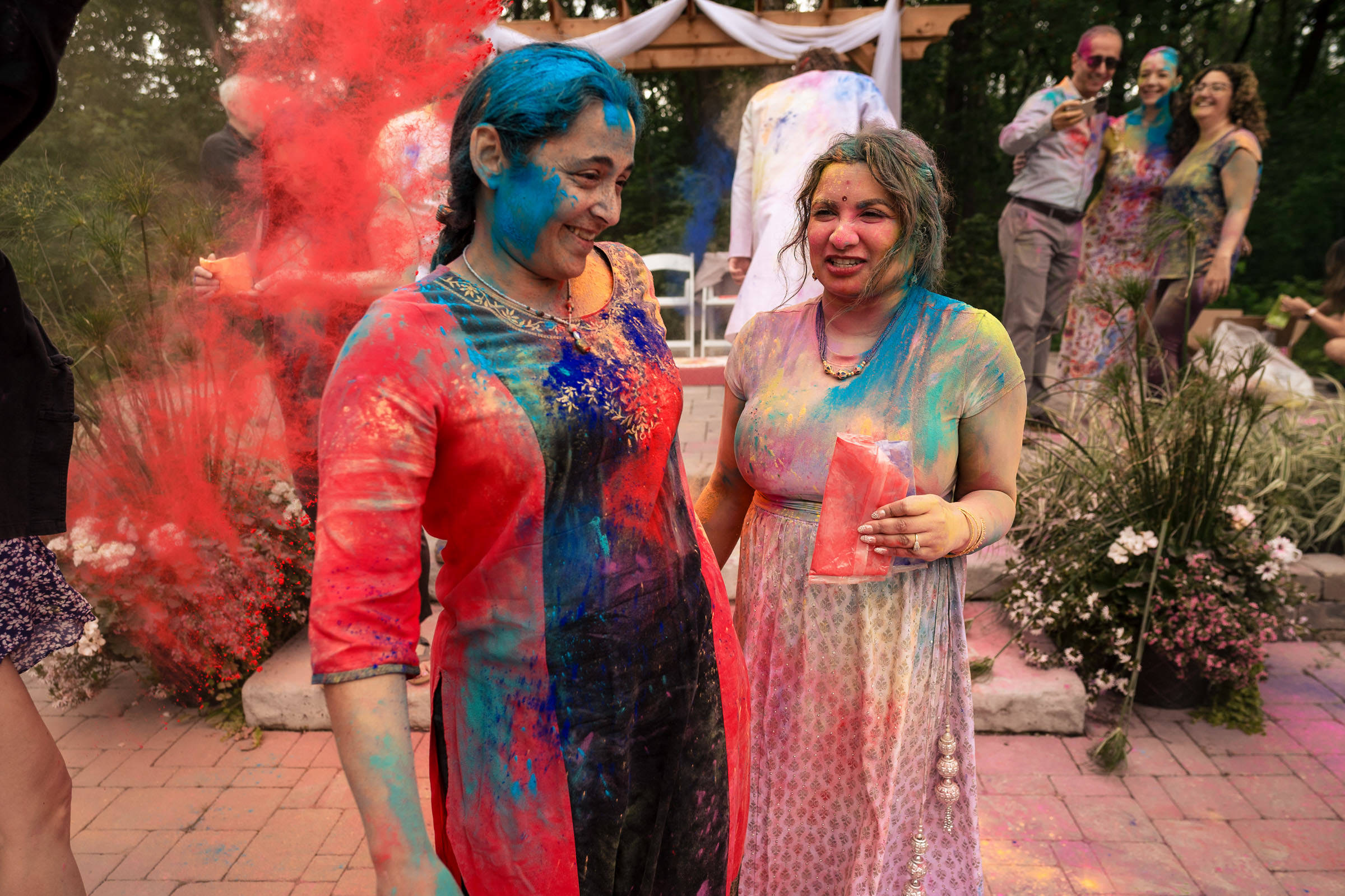 Two people, like a Winnipeg wedding, covered in colorful powder and smiling outdoors.