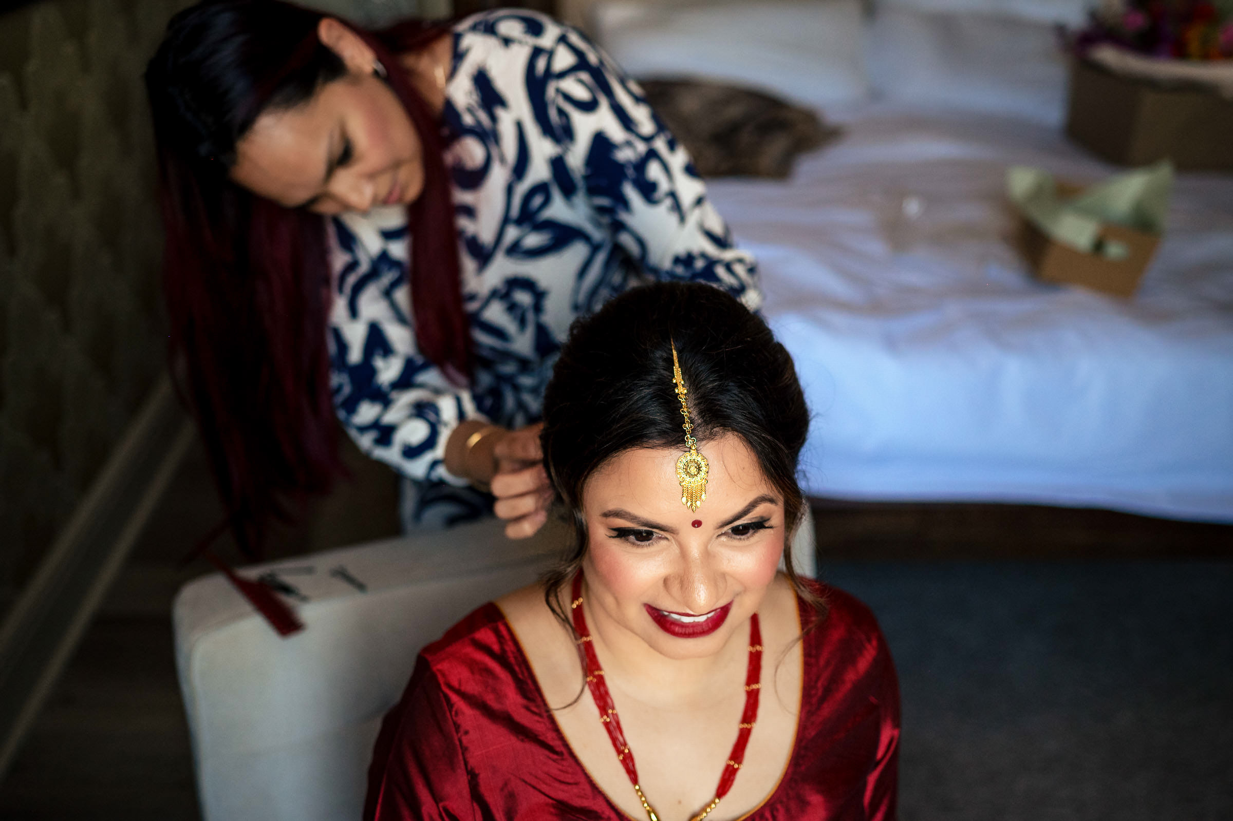 A woman in a red dress and gold jewelry, styled for a Winnipeg wedding.