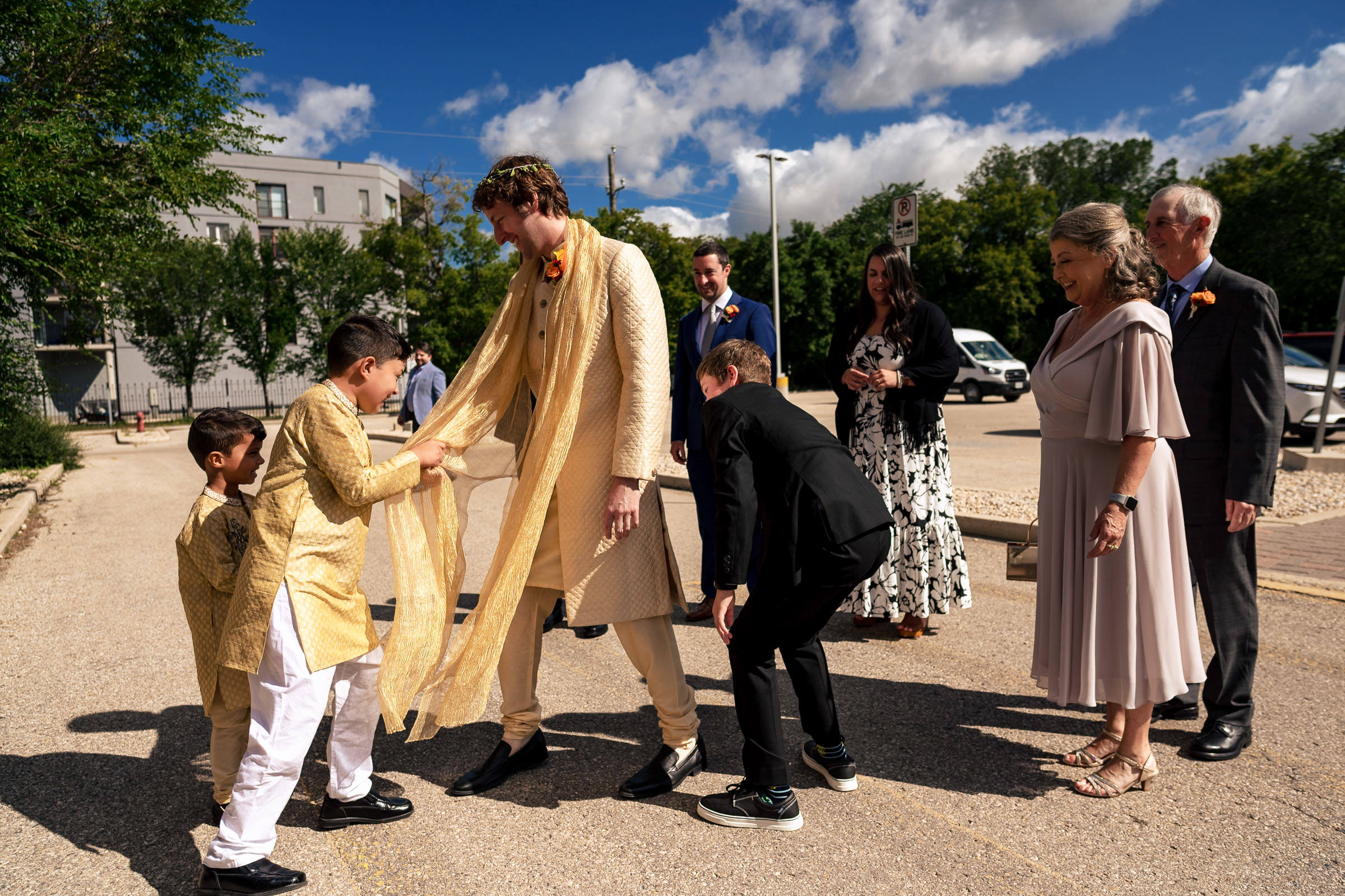 A man in traditional attire at a sunny Winnipeg wedding surrounded by cheerful guests.