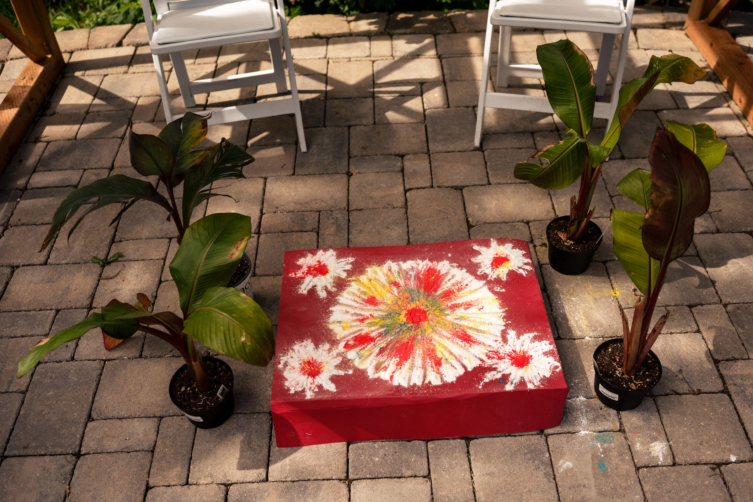 Winnipeg wedding-inspired red floral box on patio with potted plants and white chairs.