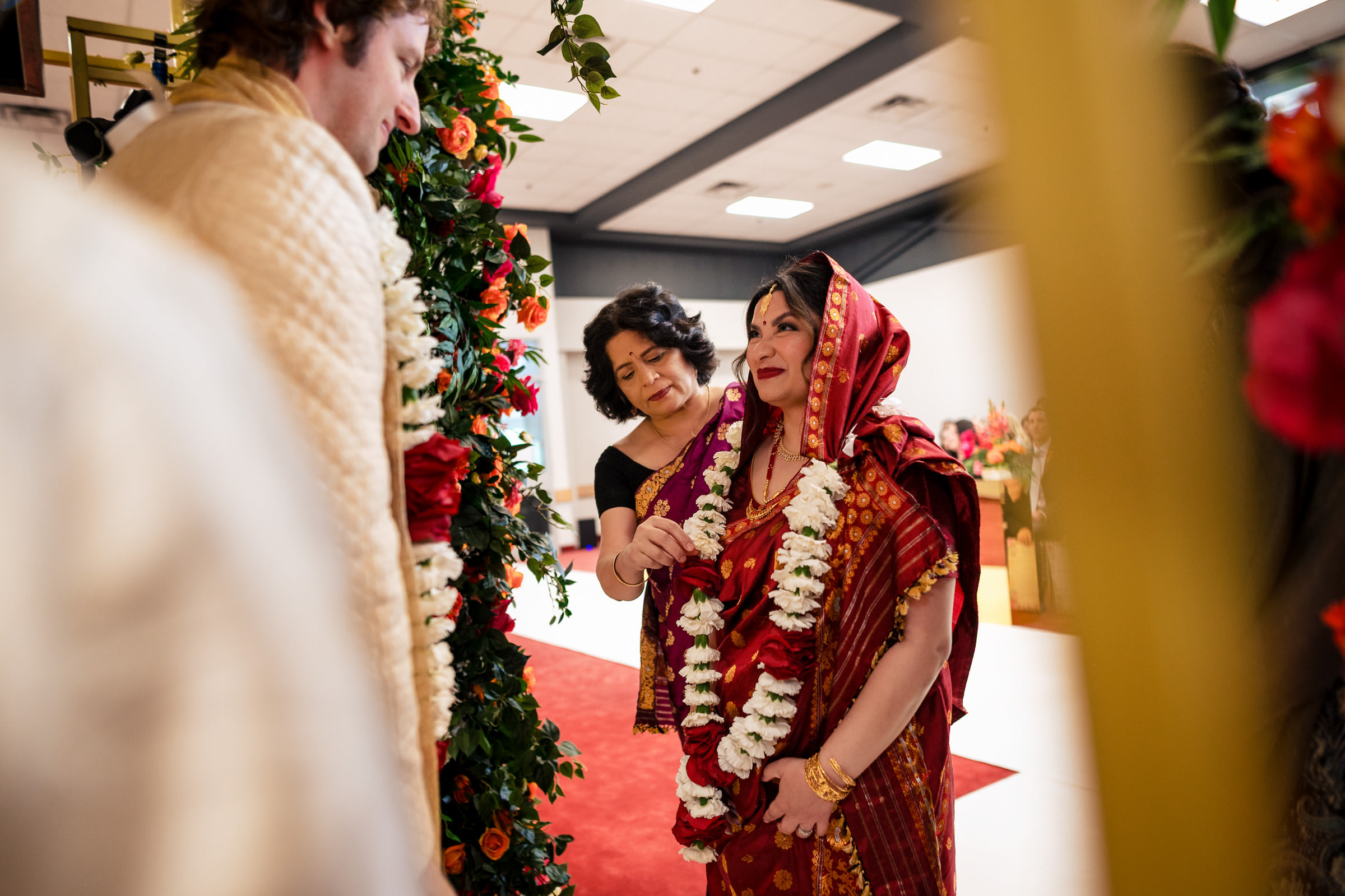 Traditional Winnipeg wedding with a couple in floral garlands, standing under an arch.
