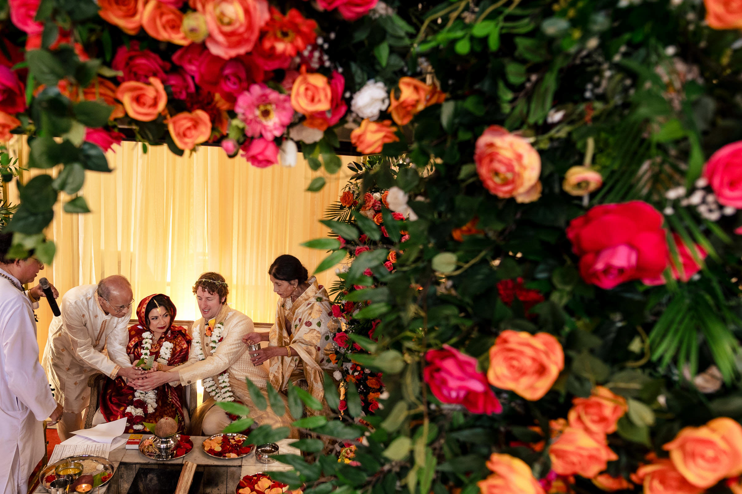 People gathered around a couple amidst vibrant flowers at a Winnipeg wedding ceremony.