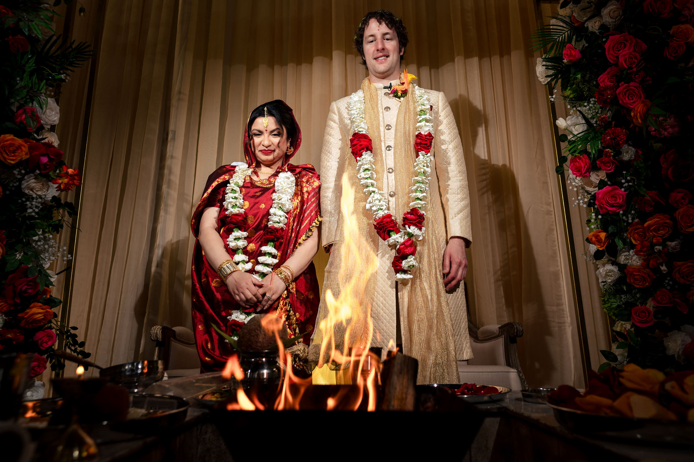 Couple stands in traditional attire at Winnipeg wedding, adorned with floral garlands.