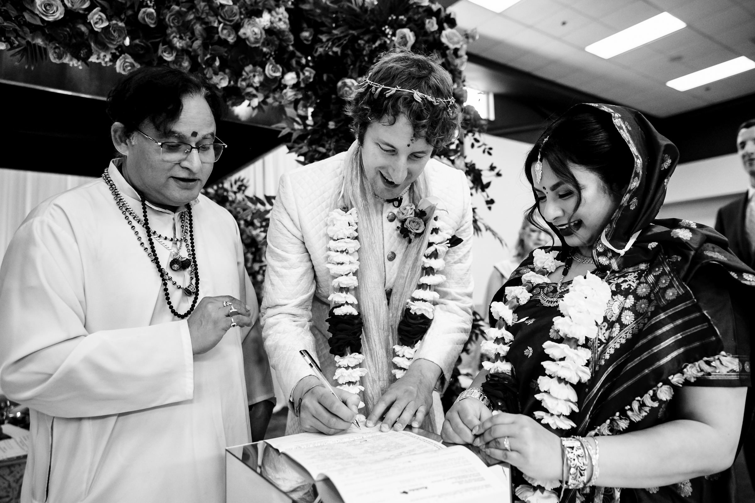Three people partake in a Winnipeg wedding signing with floral decorations.