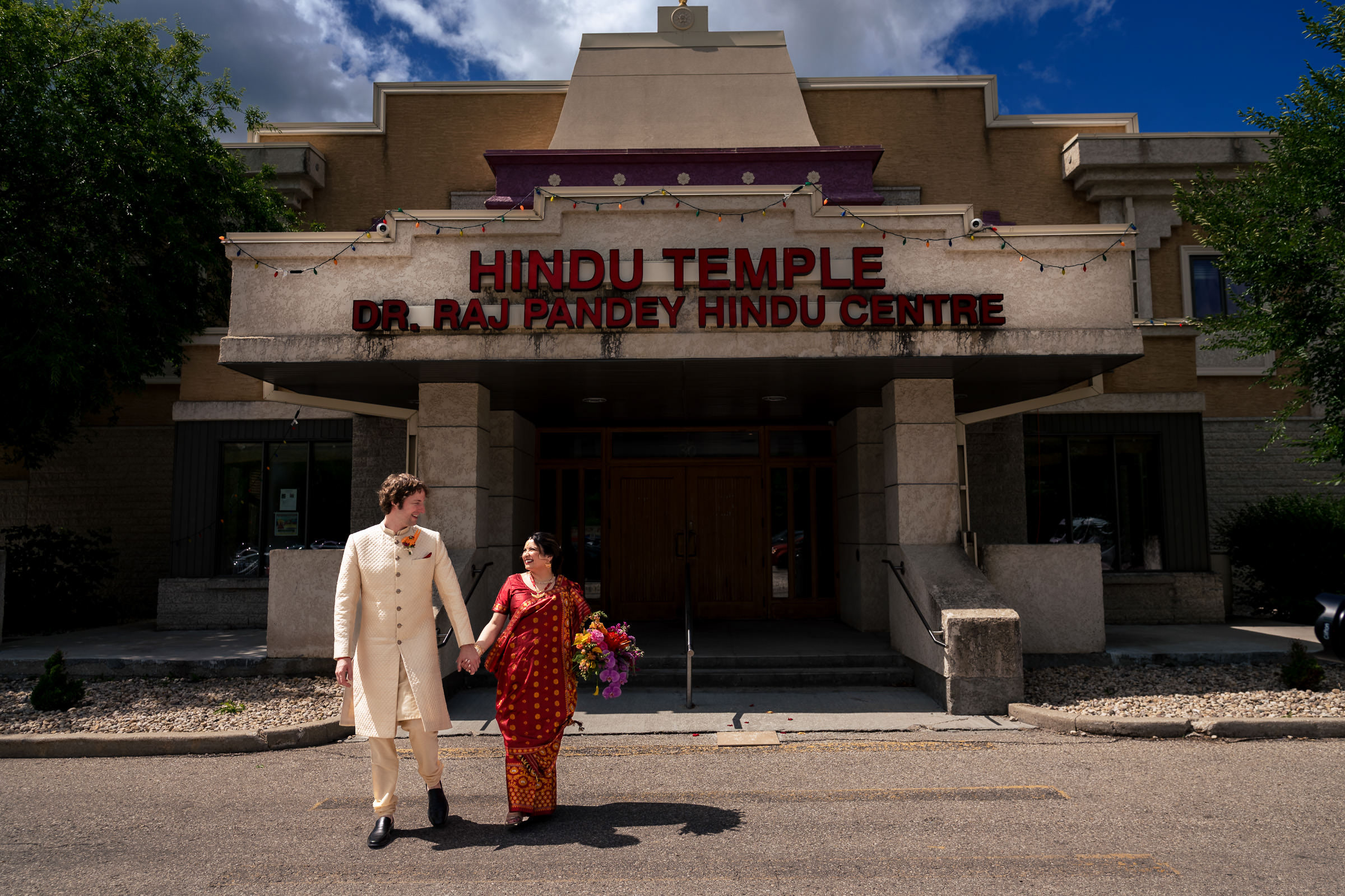 A couple in traditional attire holding hands outside a temple in Winnipeg.