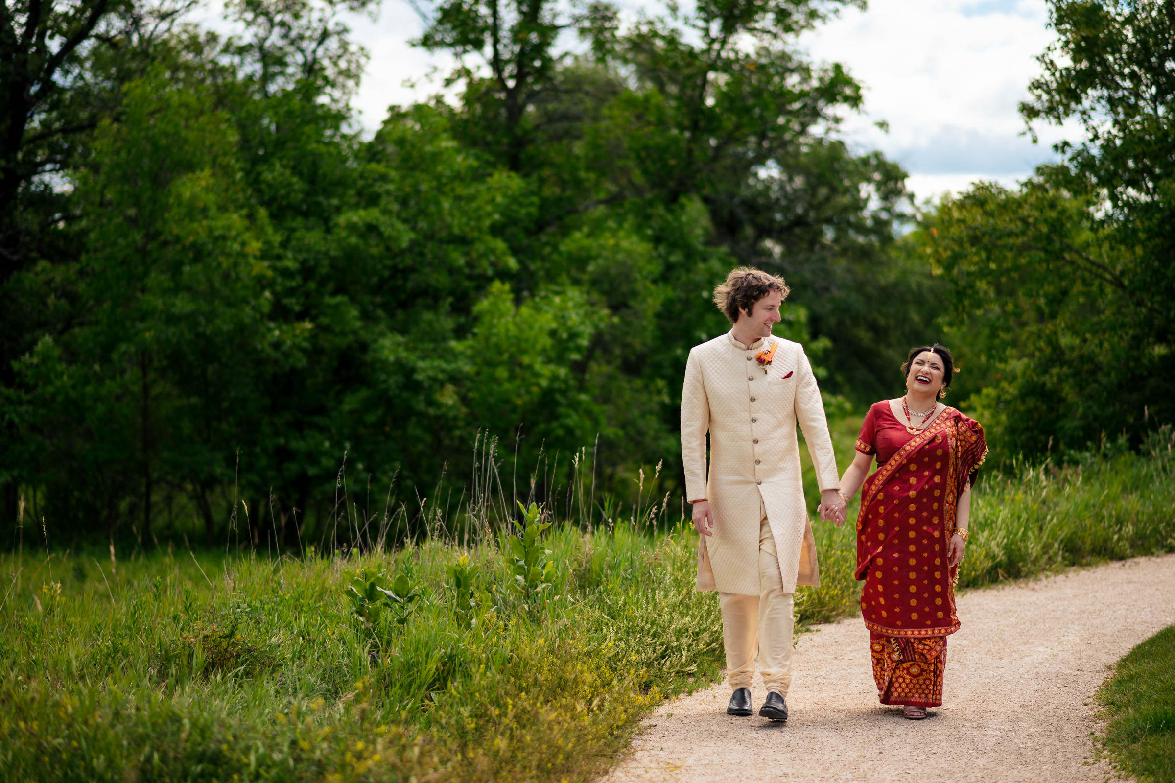 A couple walks hand in hand on a path in Winnipeg's lush green park.