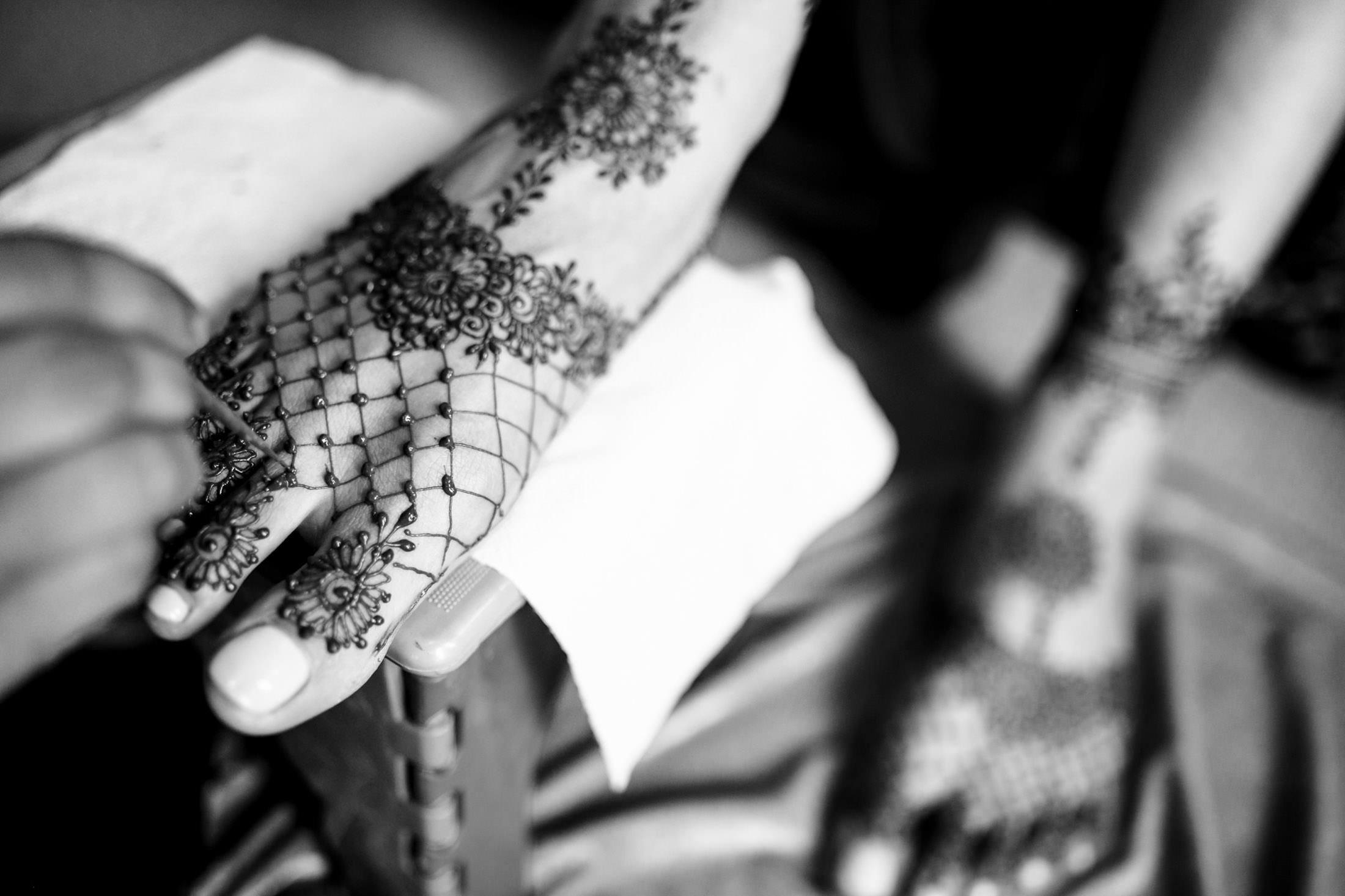 Close-up of intricate henna designs being applied to a person's foot.