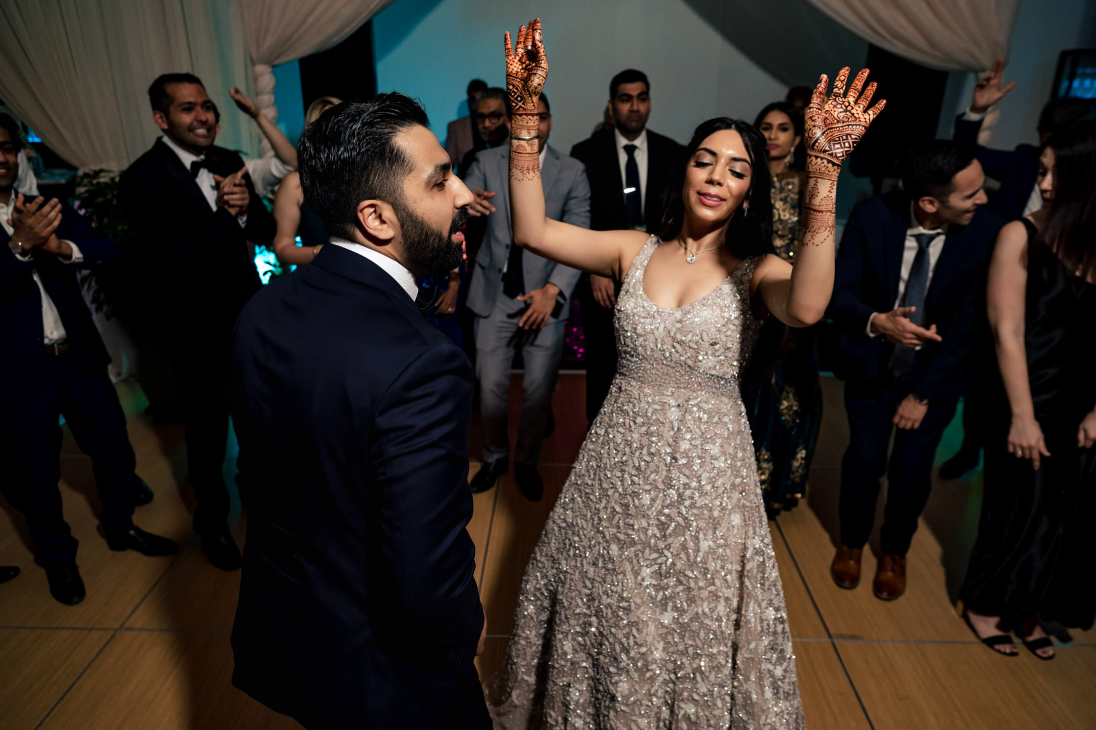 A joyful couple dances at a wedding celebration, surrounded by smiling guests.