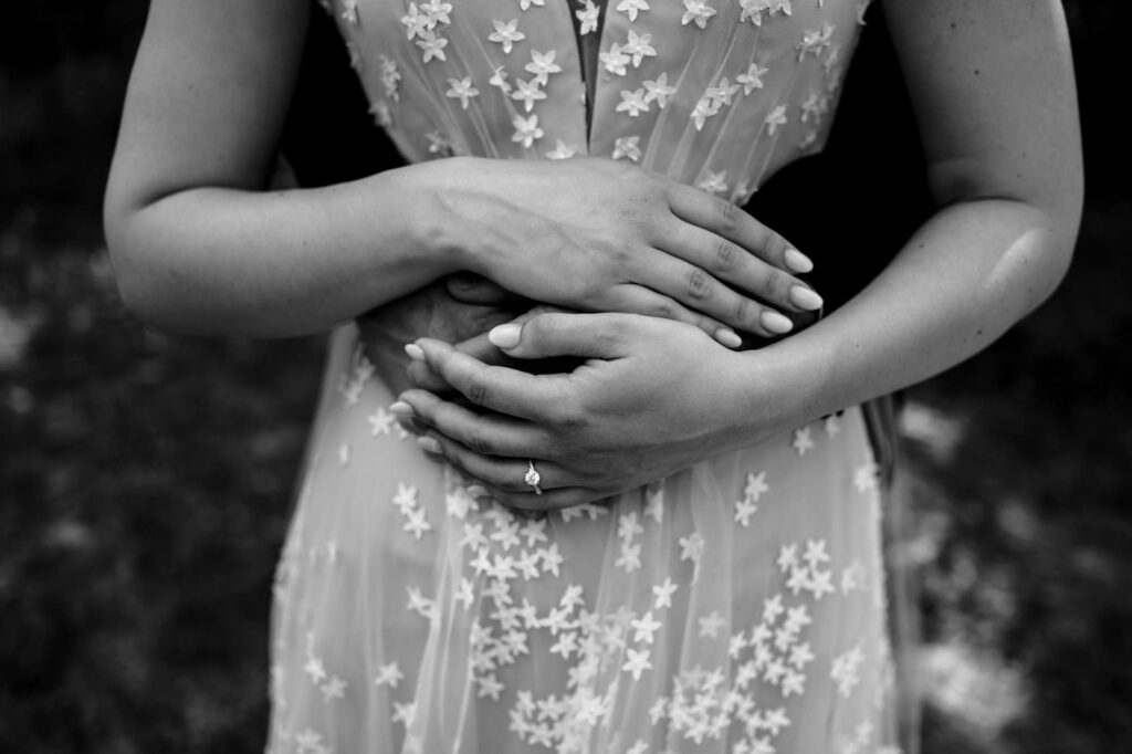 Couple embracing, woman's hand with a ring over a floral dress.
